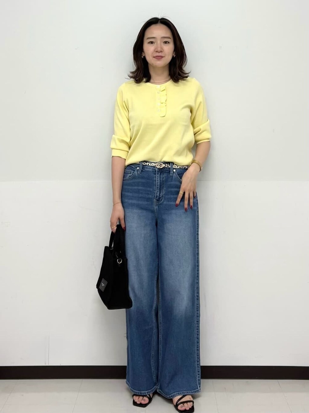 イエロー系のニット/セーター、ブルー系のデニムパンツ、ブラック系のトートバッグを着用したレディースの春コーディネートの1枚目の写真