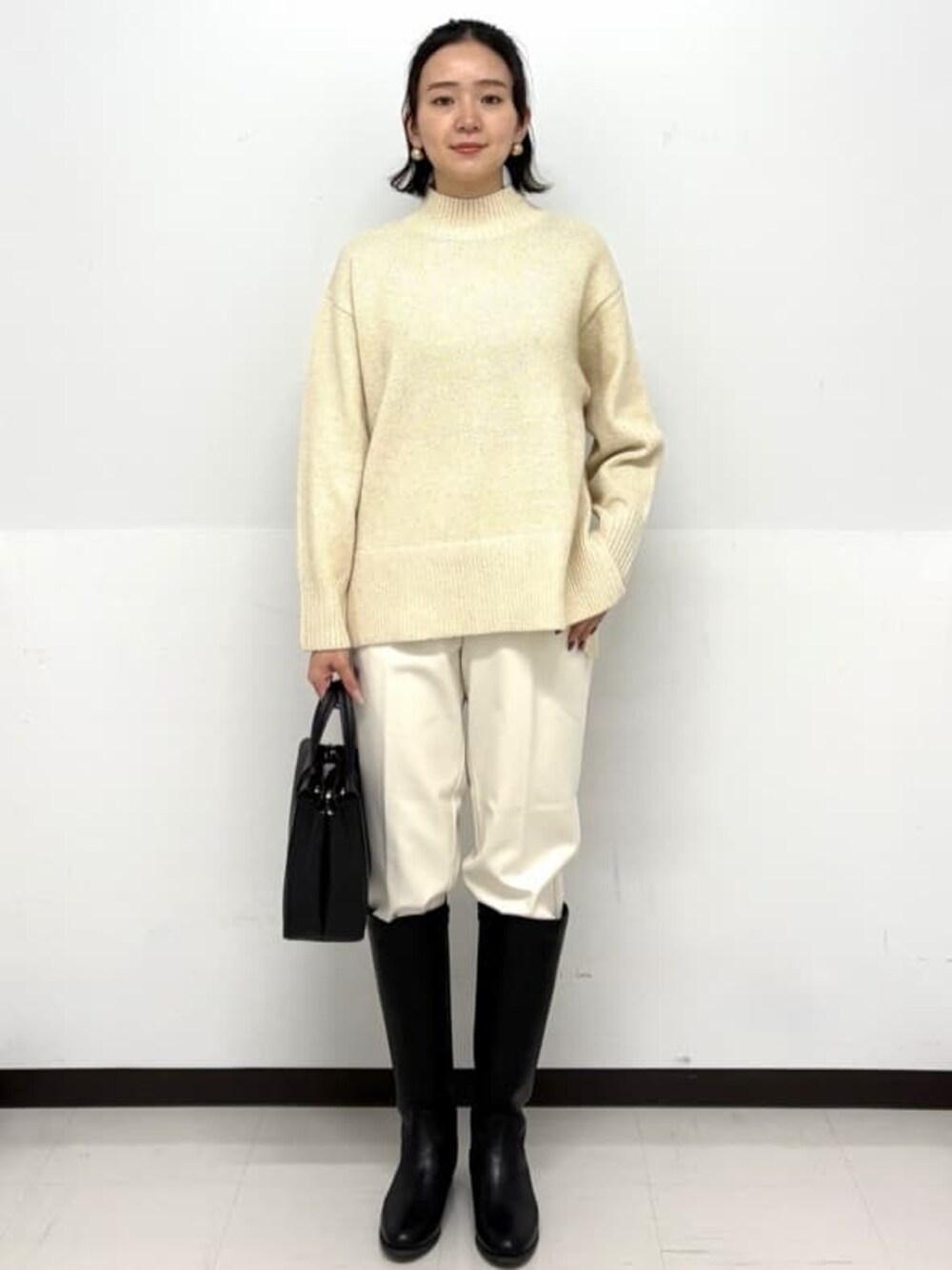 ベージュ系のニット/セーター、ホワイト系のその他パンツ、ブラック系のトートバッグを着用したレディースの秋コーディネートの1枚目の写真