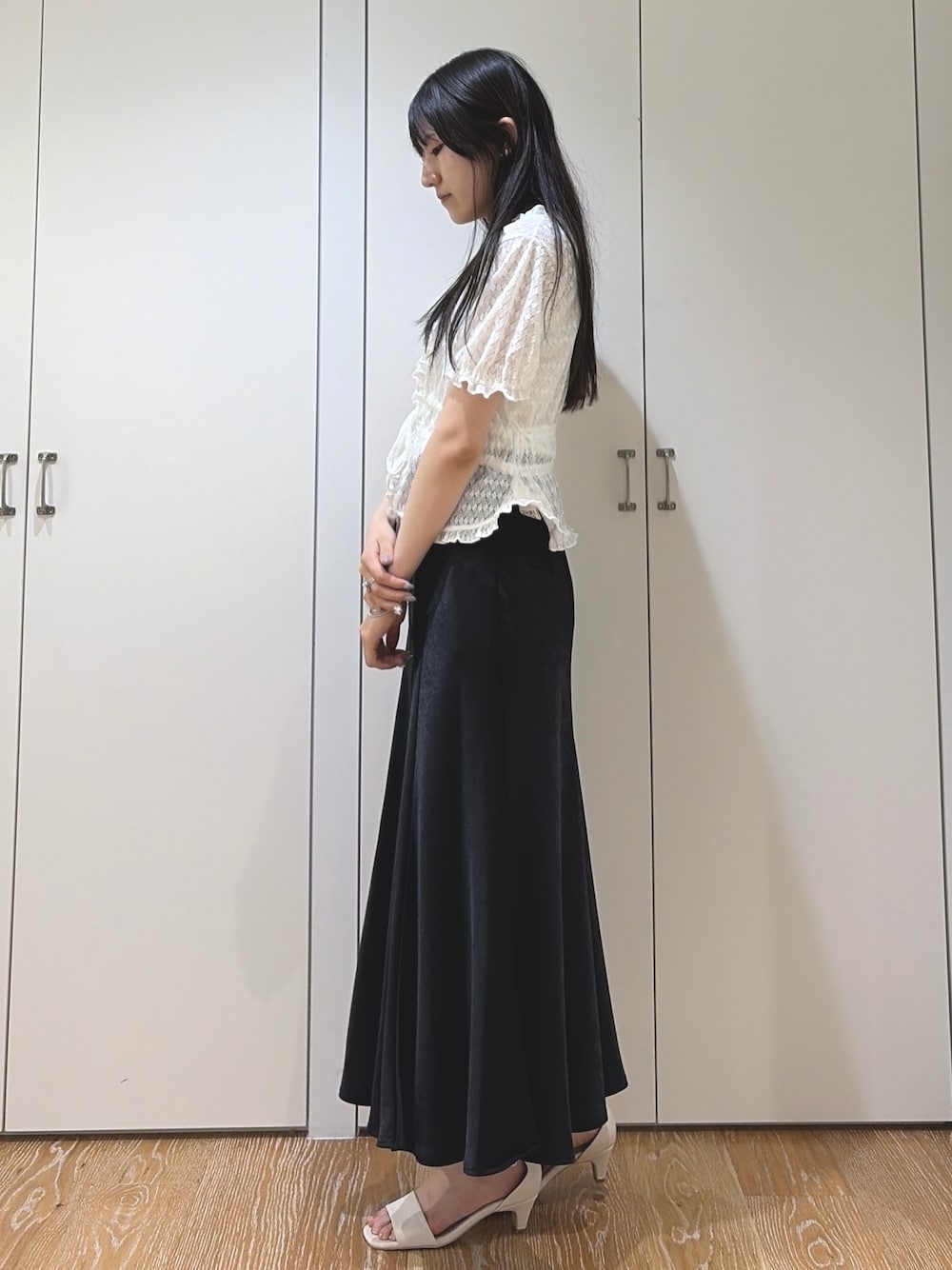 ブラック系のスカート、ホワイト系のサンダル、ホワイト系のカーディガン/ボレロを着用したレディースの夏コーディネートの1枚目の写真