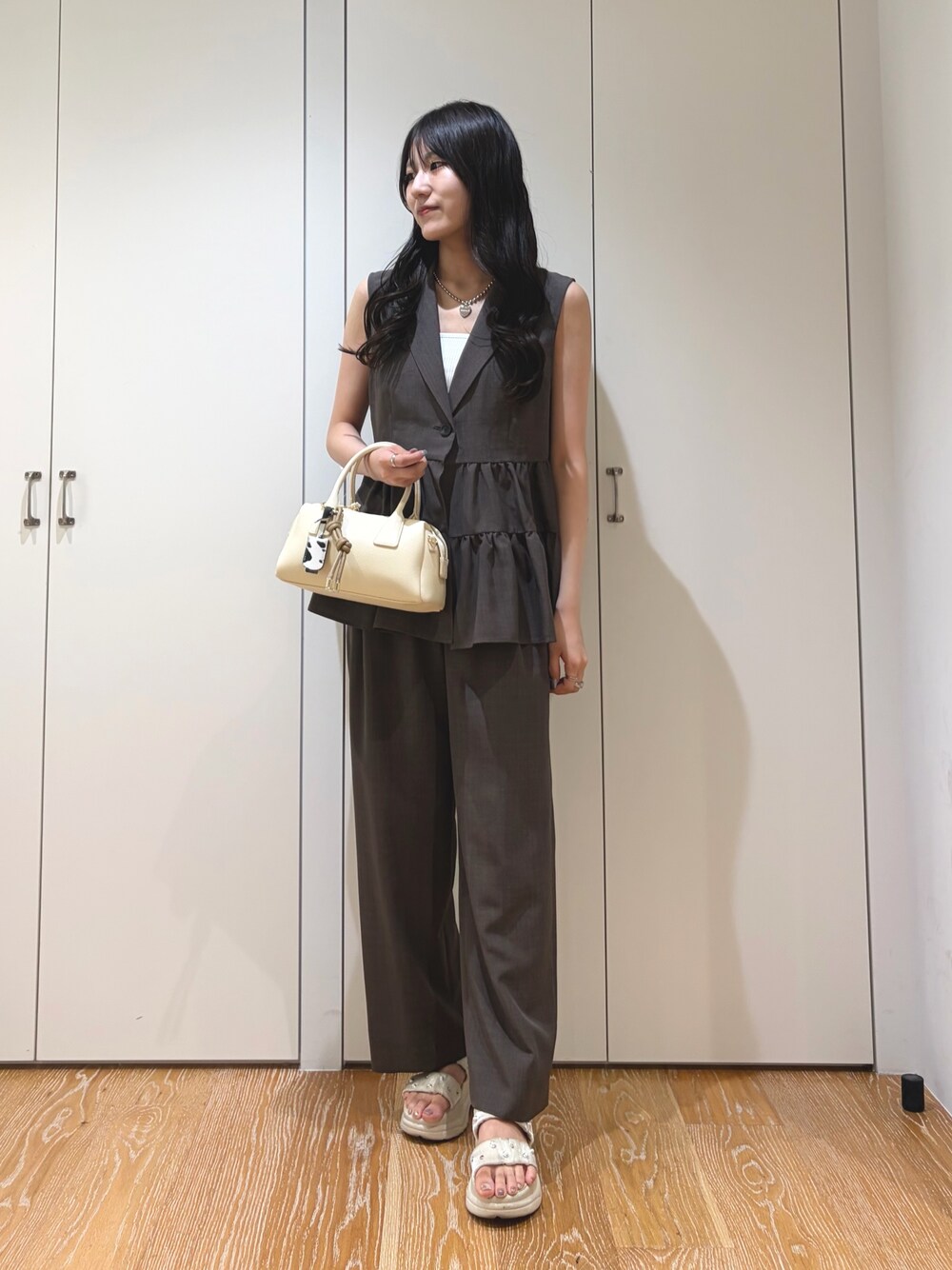 ブラウン系のベスト、ブラウン系のその他パンツ、ホワイト系のボストンバッグを着用したレディースの夏コーディネートの1枚目の写真