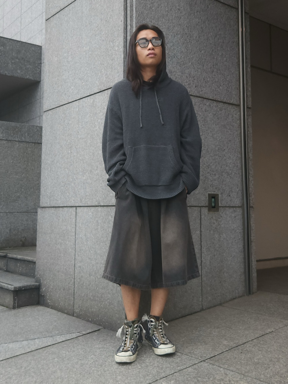 グレー系のパーカー、ブラック系のデニムパンツ、ブラック系のスニーカーを着用したメンズの秋コーディネートの1枚目の写真