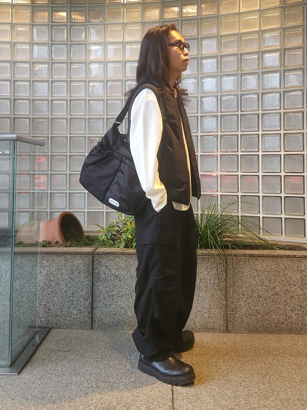 ブラック系のショルダーバッグ、ホワイト系のTシャツ/カットソー、ブラック系のダウンベストを着用したメンズの秋コーディネートの1枚目の写真