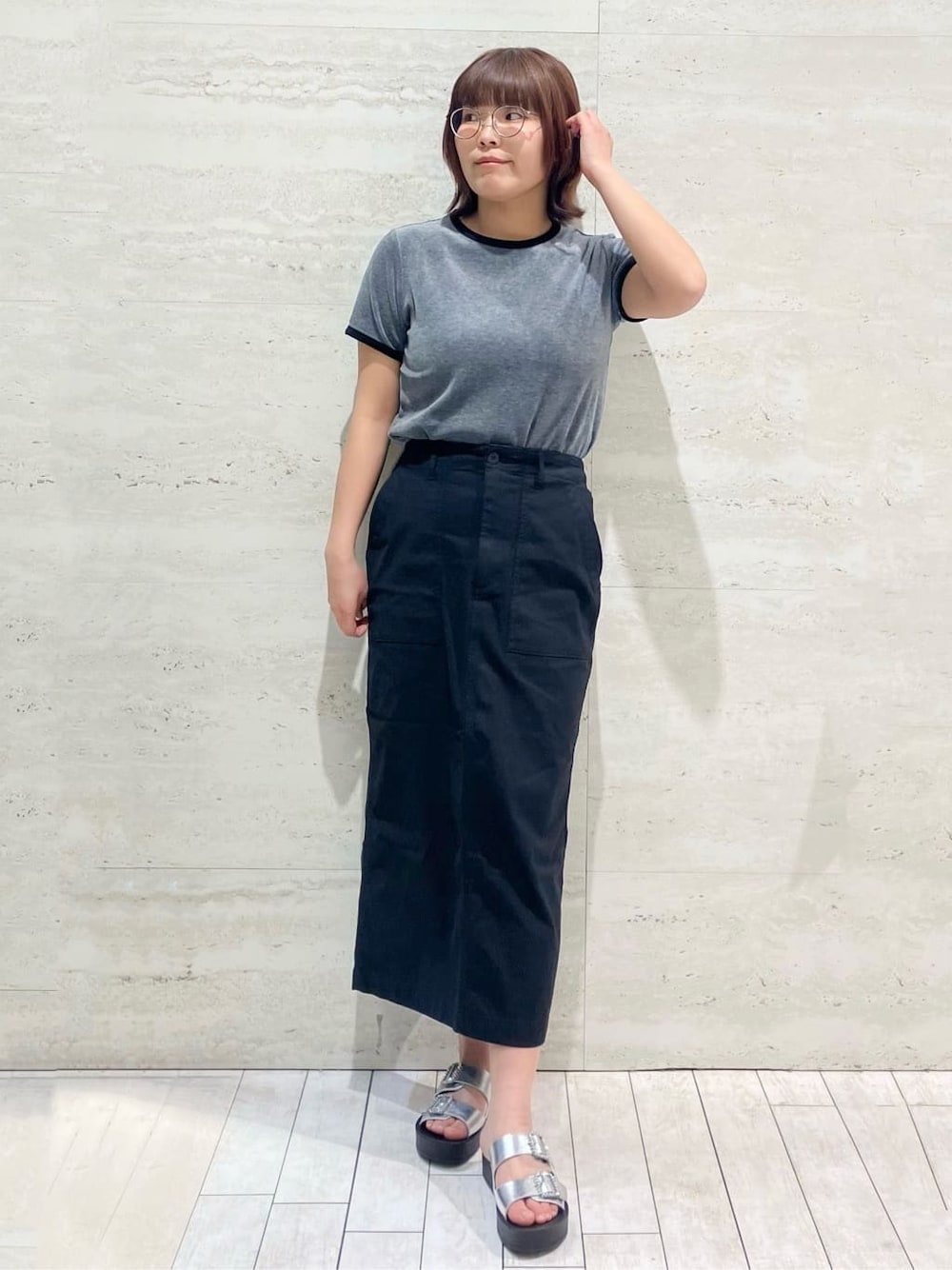 グレー系のTシャツ/カットソー、ブラック系のスカート、シルバー系のサンダルを着用したレディースの春コーディネートの1枚目の写真