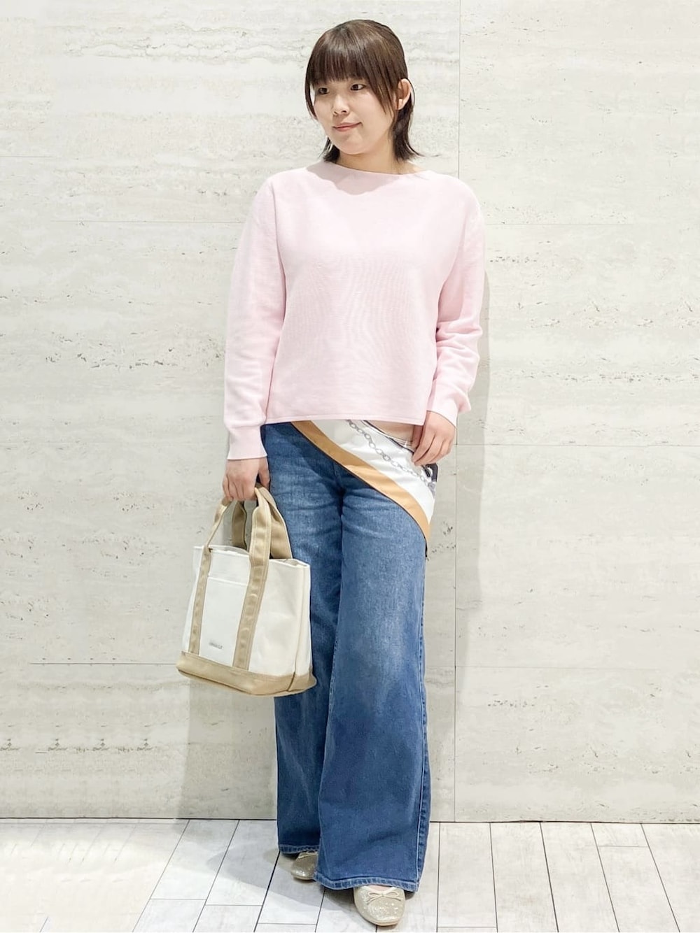 ピンク系のニット/セーター、ブルー系のデニムパンツ、ベージュ系のトートバッグを着用したレディースの春コーディネートの1枚目の写真
