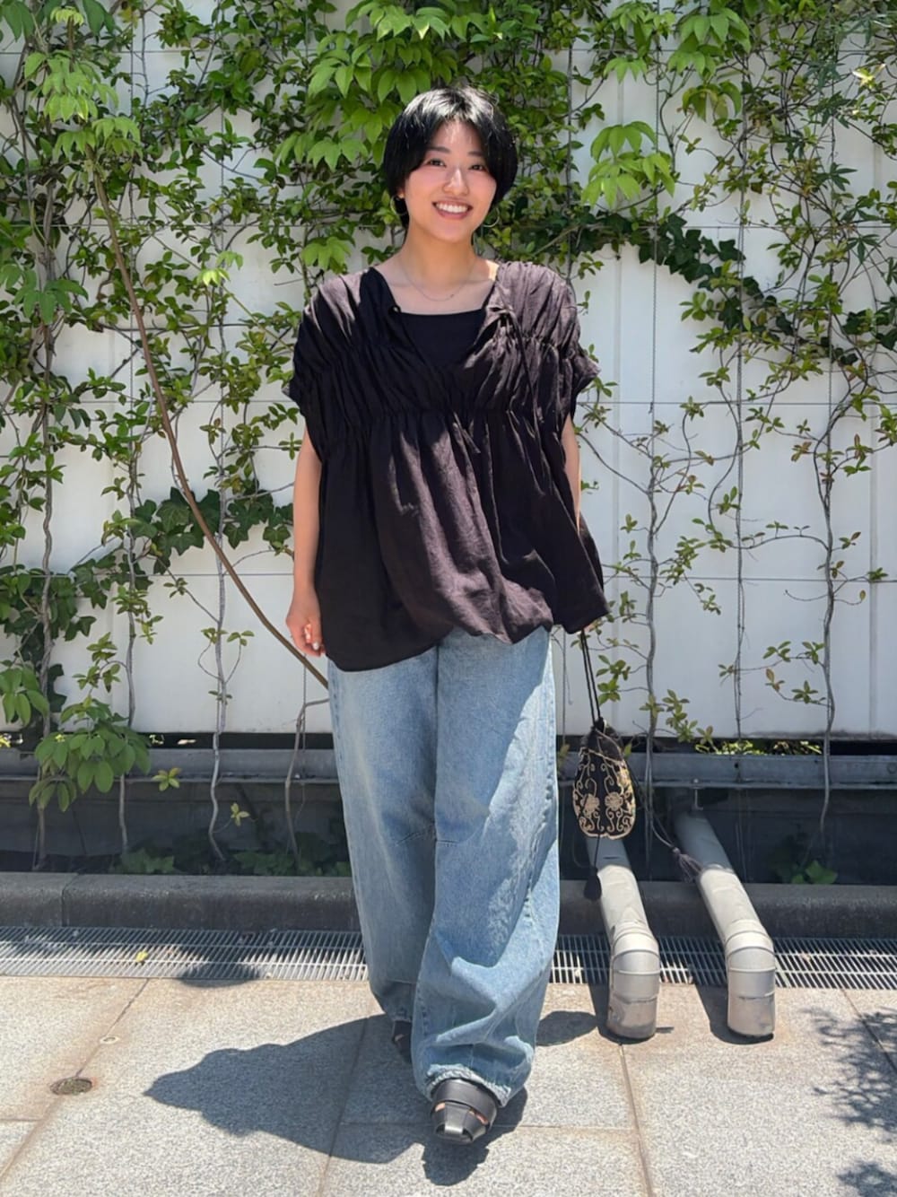 ブラック系のハンドバッグ、ブルー系のデニムパンツ、ブラック系のシャツ/ブラウスを着用したレディースの夏コーディネートの1枚目の写真