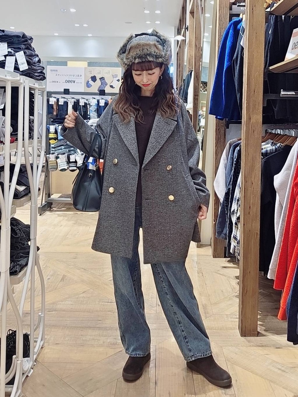 ブラック系のショルダーバッグ、ブルー系のデニムパンツ、グレー系のチェスターコートを着用したレディースの冬コーディネートの1枚目の写真