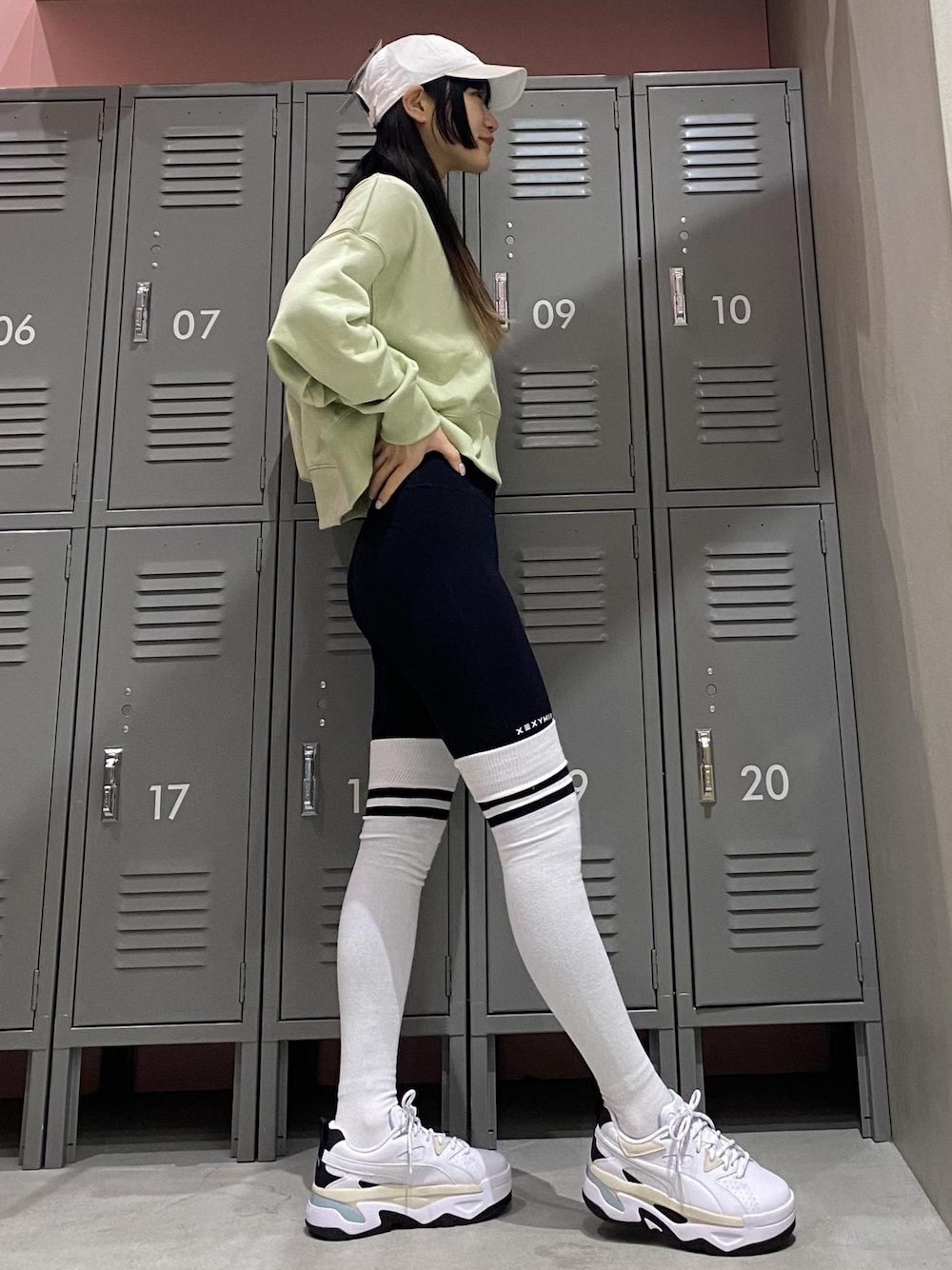 ホワイト系のスニーカー、グリーン系のスウェット、ブラック系のレギンス/スパッツを着用したレディースの冬コーディネートの1枚目の写真