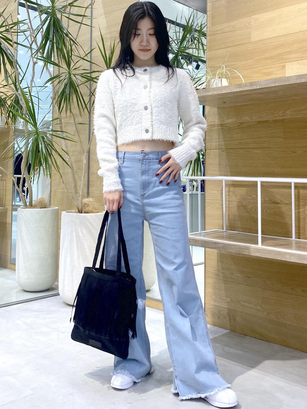 ホワイト系のスニーカー、ブルー系のデニムパンツ、ブラック系のトートバッグを着用したレディースの秋コーディネートの1枚目の写真