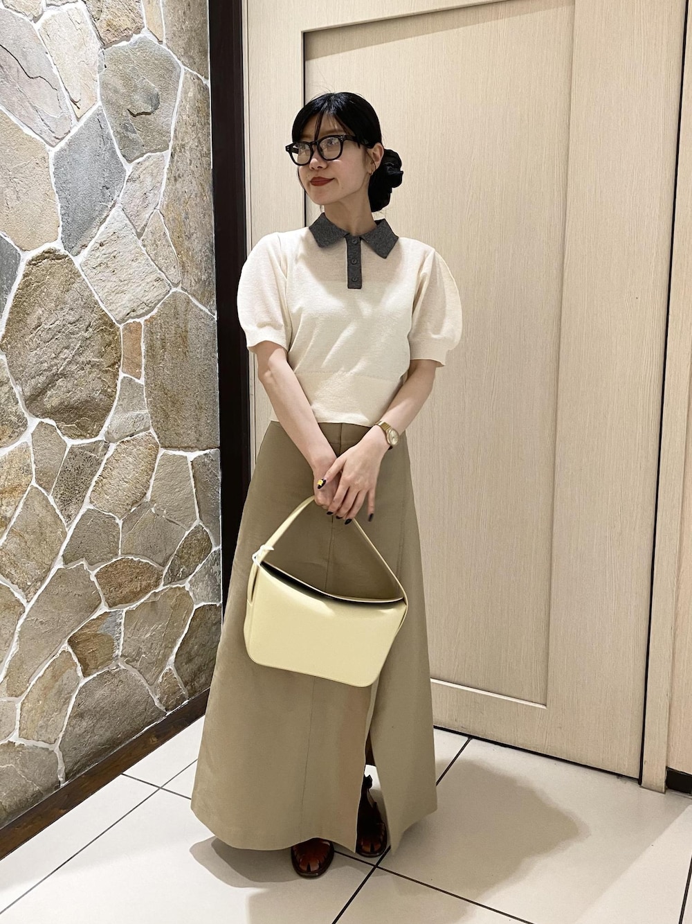 ベージュ系のショルダーバッグ、ベージュ系のスカート、ホワイト系のポロシャツを着用したレディースの春コーディネートの1枚目の写真