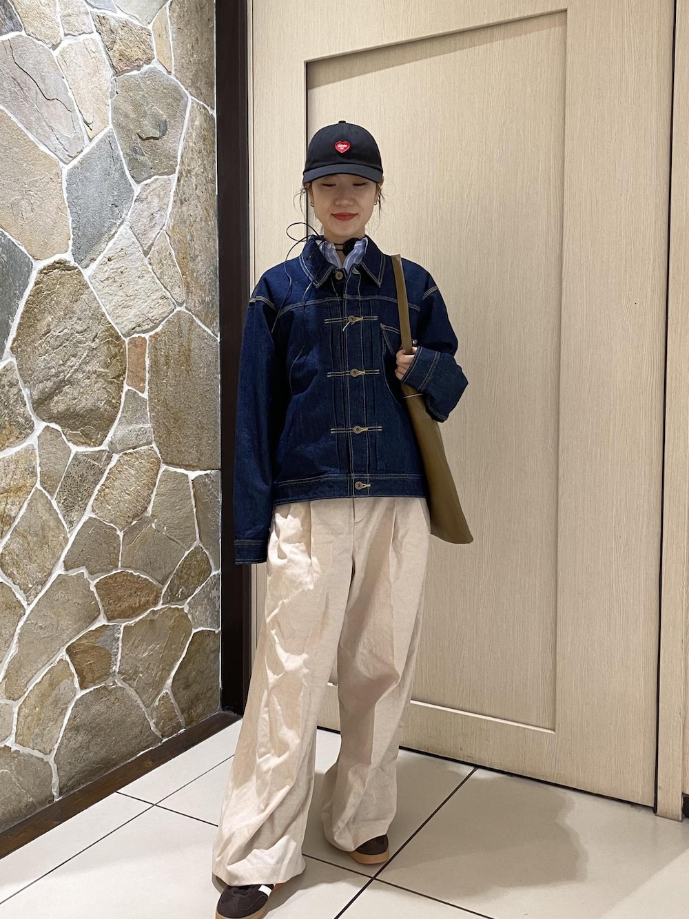 グリーン系のショルダーバッグ、ブルー系のデニムジャケット、ホワイト系のその他パンツを着用したレディースの冬コーディネートの1枚目の写真