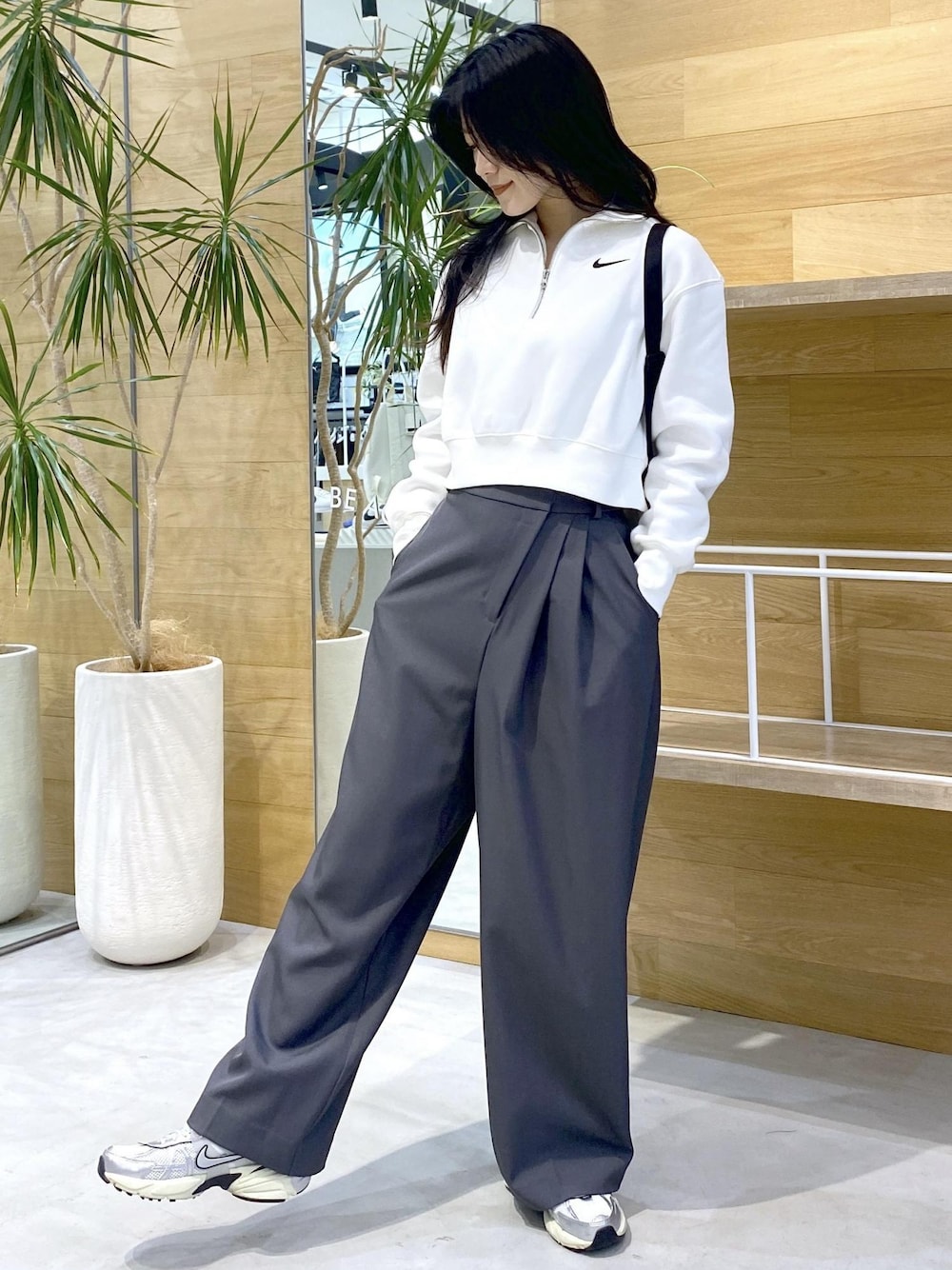 グレー系のスラックス、ホワイト系のスニーカーを着用したレディースの秋コーディネートの1枚目の写真