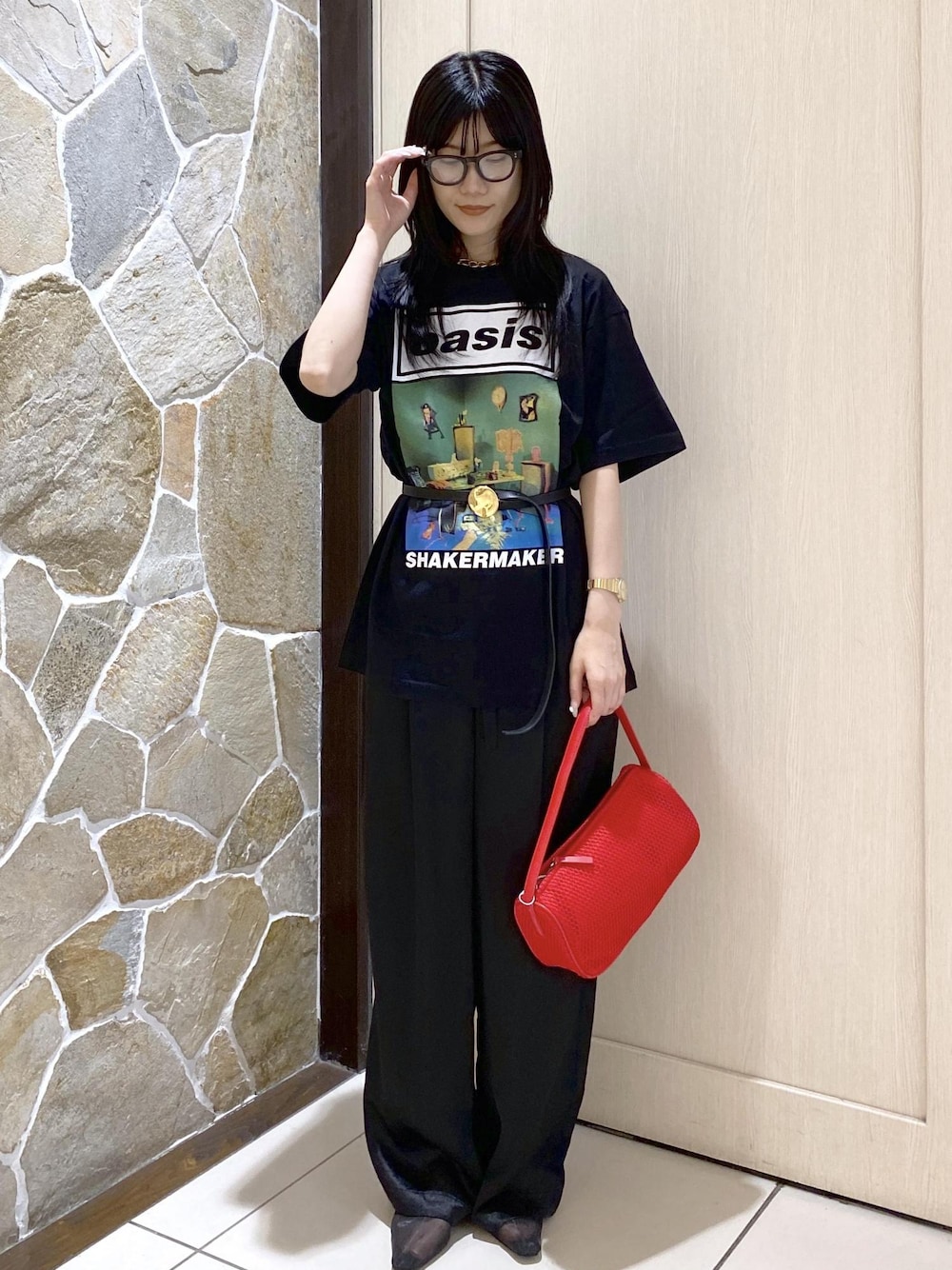 ブラック系のパンプス、ブラック系のスラックス、レッド系のハンドバッグを着用したレディースの夏コーディネートの1枚目の写真