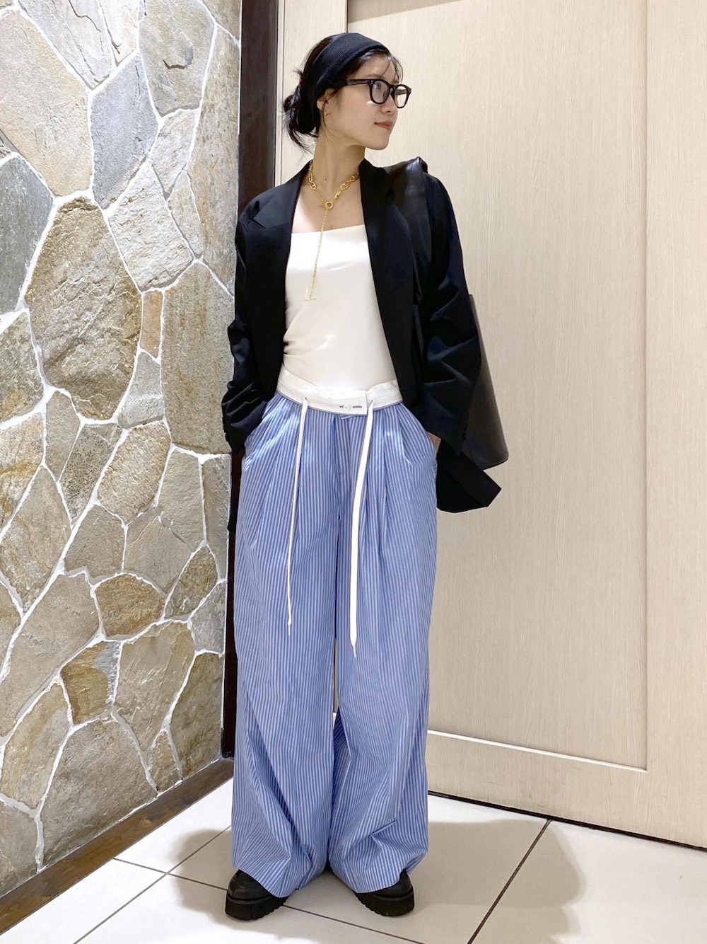 ブルー系のスラックス、ブラック系のテーラードジャケット、ブラック系のローファーを着用したレディースの秋コーディネートの1枚目の写真