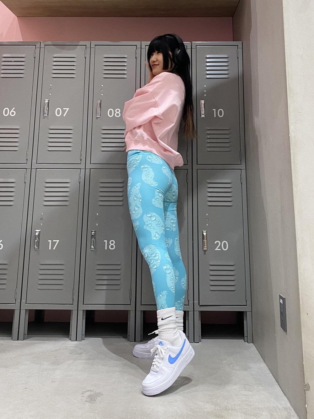 ピンク系のスウェット、ホワイト系のスニーカー、ブルー系のレギンス/スパッツを着用したレディースの冬コーディネートの1枚目の写真