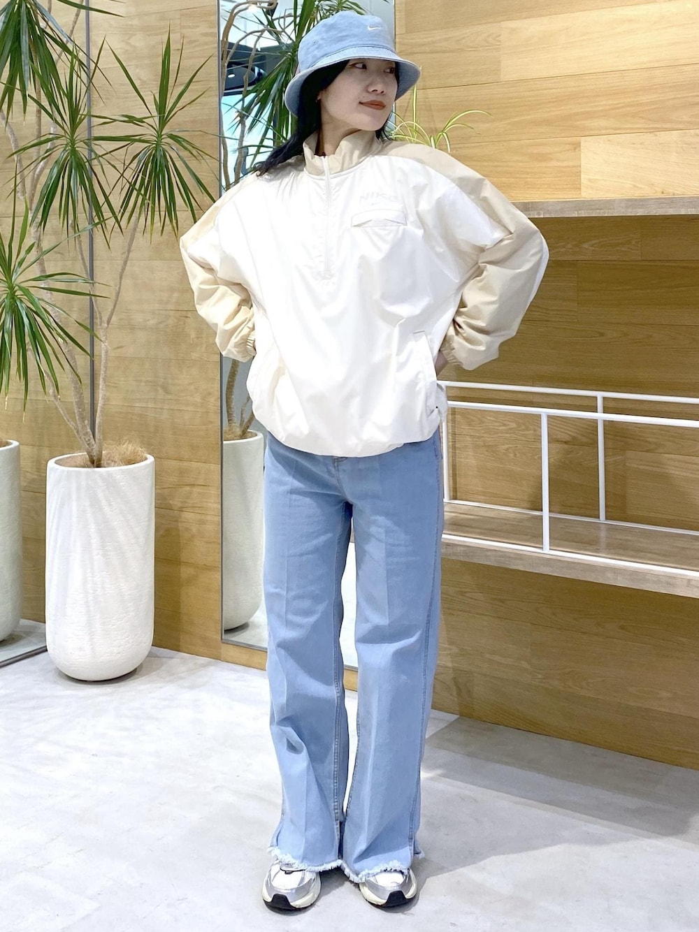 ホワイト系のスニーカー、ブルー系のデニムパンツ、ブルー系のハットを着用したレディースの秋コーディネートの1枚目の写真