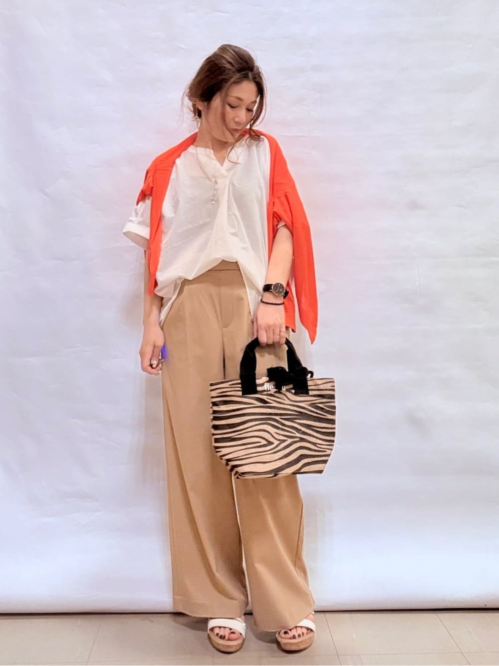 オレンジ系のカーディガン/ボレロ、ホワイト系のシャツ/ブラウス、ベージュ系のその他パンツを着用したレディースの春コーディネートの1枚目の写真