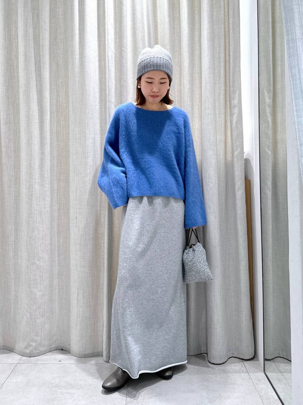 ブルー系のニット/セーター、シルバー系のショルダーバッグ、グレー系のスカートを着用したレディースの秋コーディネートの1枚目の写真