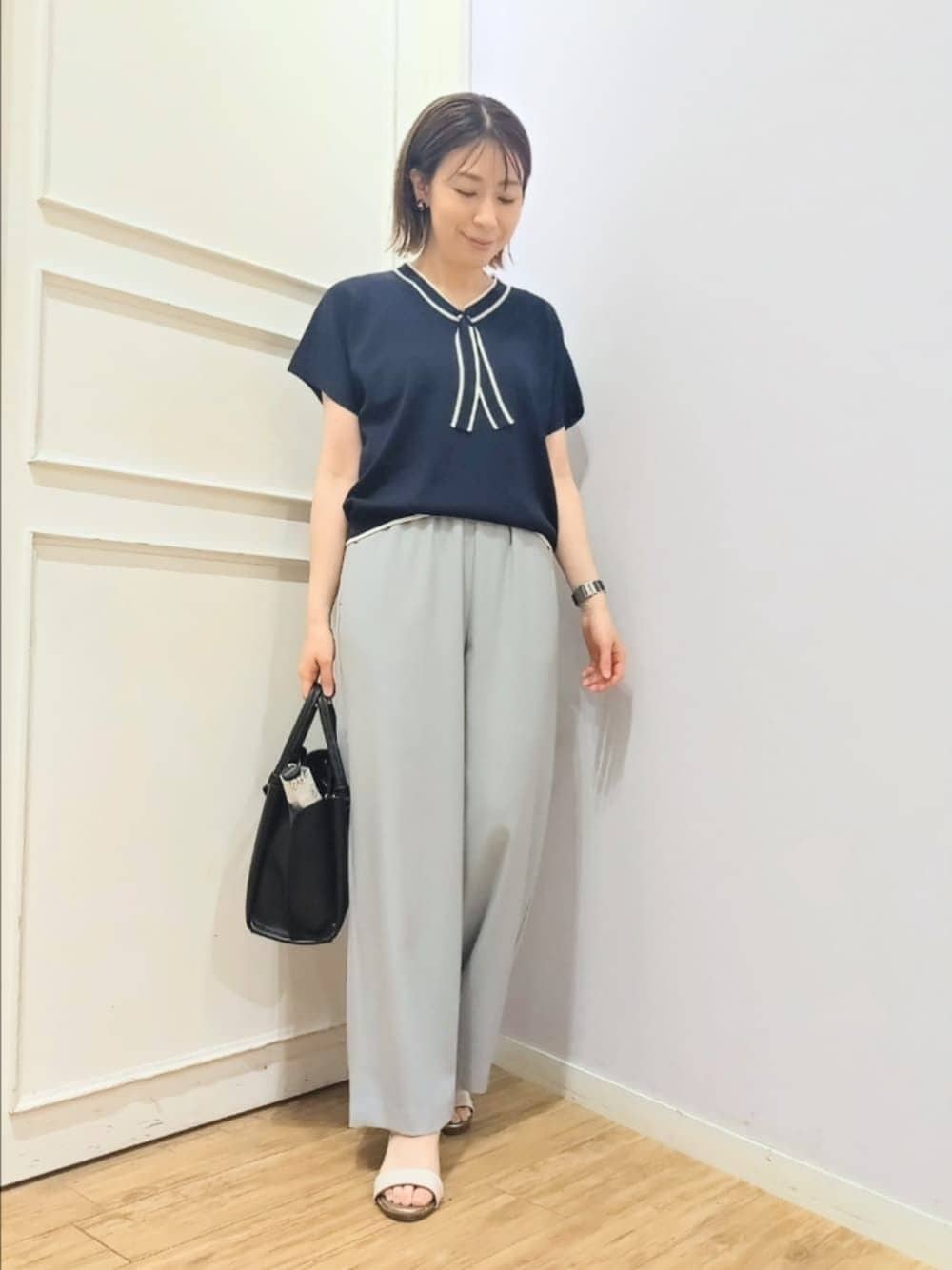 ブルー系のニット/セーター、グレー系のその他パンツ、ブラック系のトートバッグを着用したレディースの春コーディネートの1枚目の写真