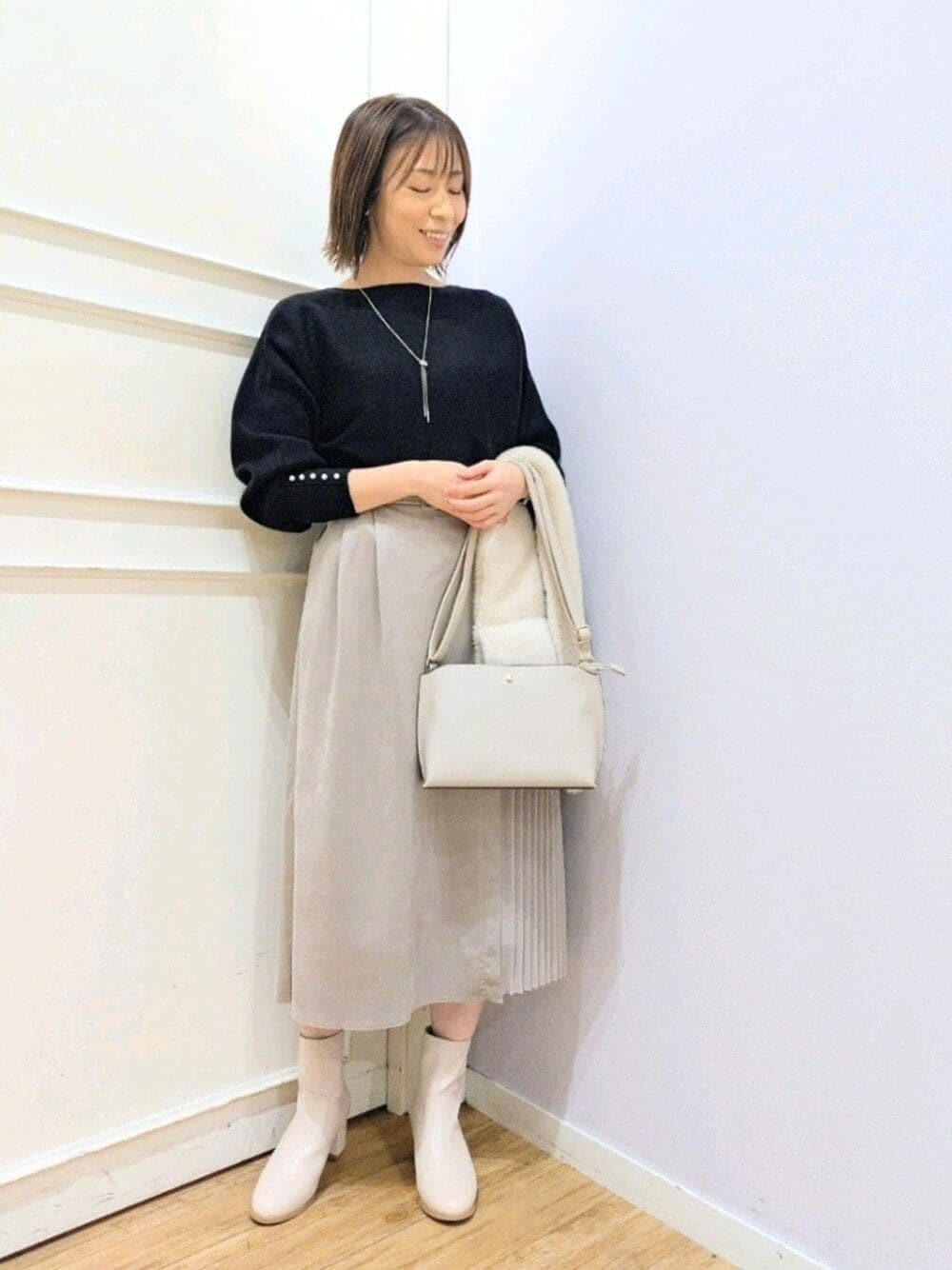 ブラック系のニット/セーター、グレー系のショルダーバッグ、ホワイト系のブーツを着用したレディースの冬コーディネートの1枚目の写真