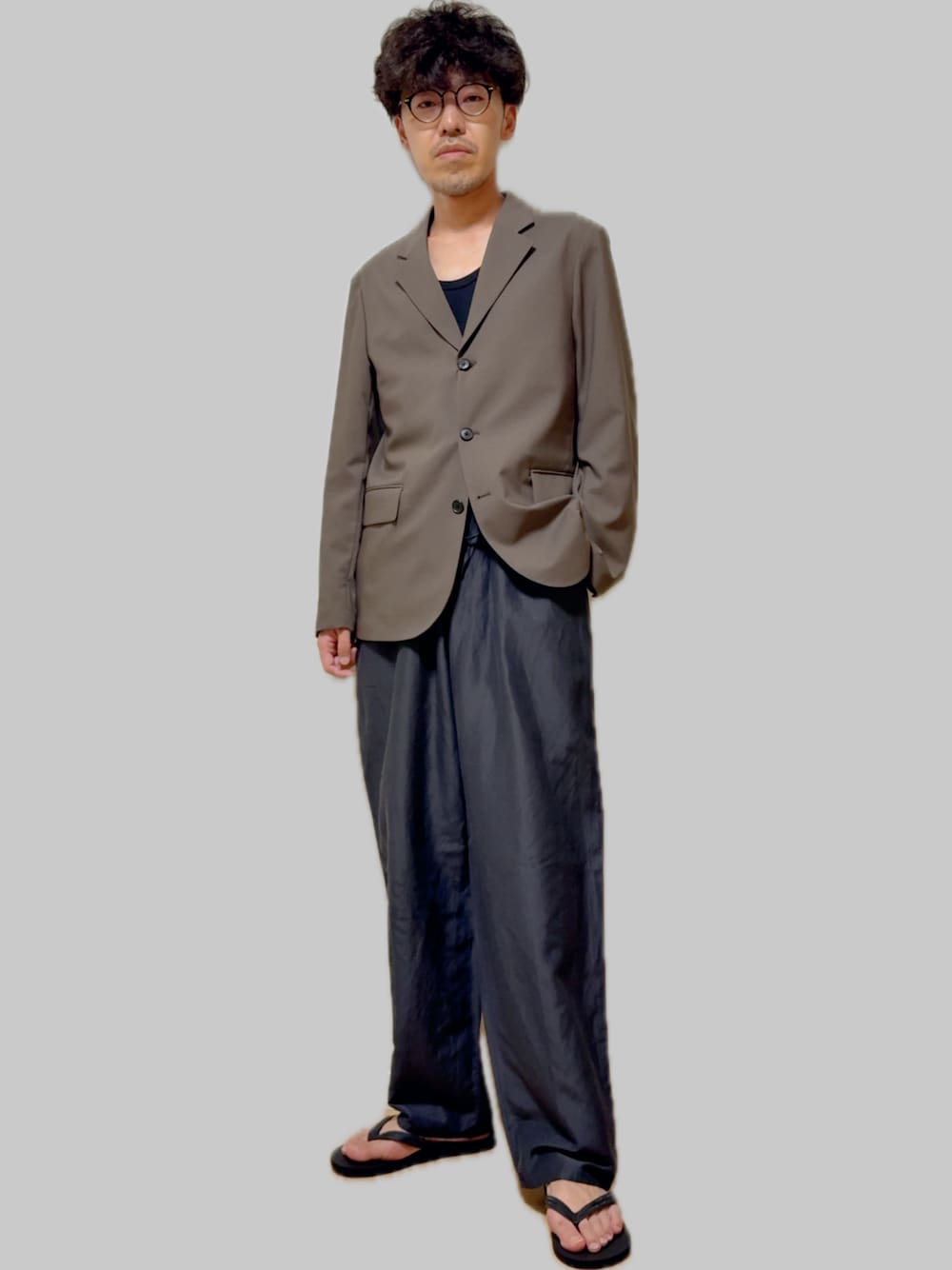 グレー系のテーラードジャケット、グレー系のその他パンツ、ブラック系のサンダルを着用したメンズの秋コーディネートの1枚目の写真