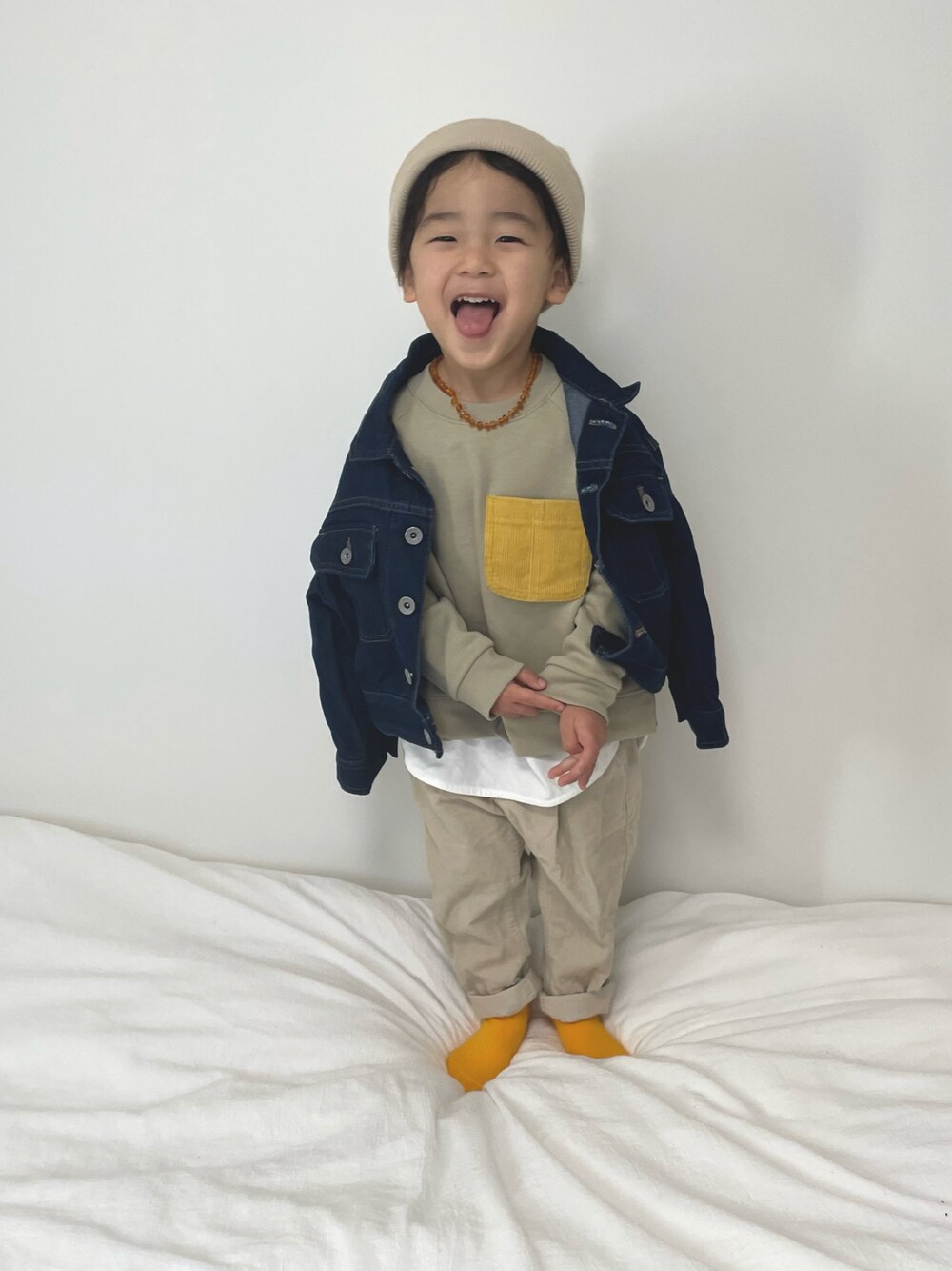 ベージュ系のパンツ、ブルー系のデニムジャケット、ベージュ系のスウェットを着用したキッズの冬コーディネートの1枚目の写真