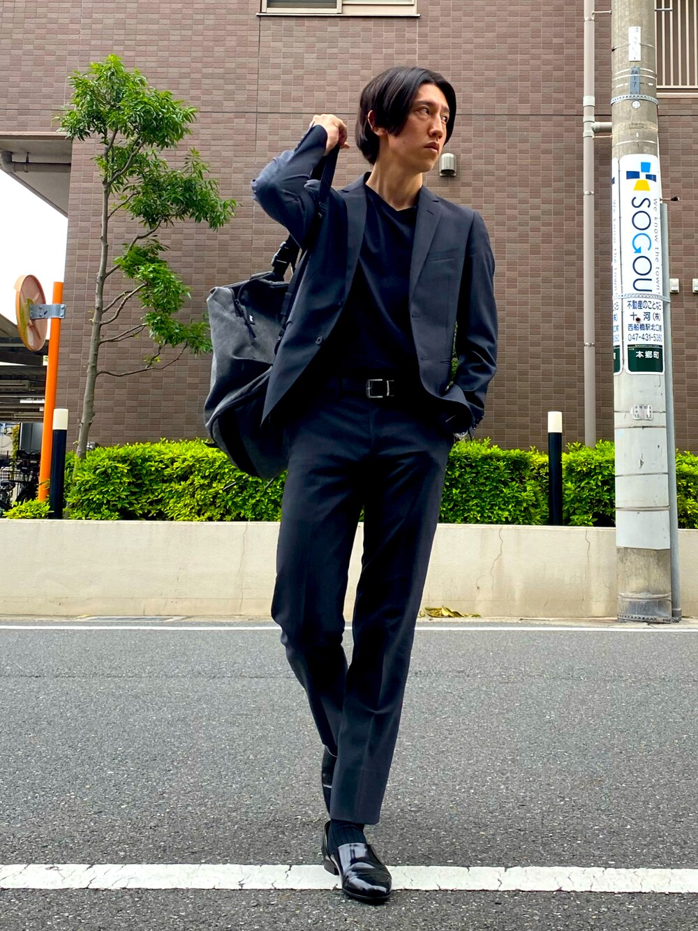 グレー系のショルダーバッグ、ブラック系のTシャツ/カットソー、ブラック系のドレスシューズを着用したメンズの夏コーディネートの1枚目の写真