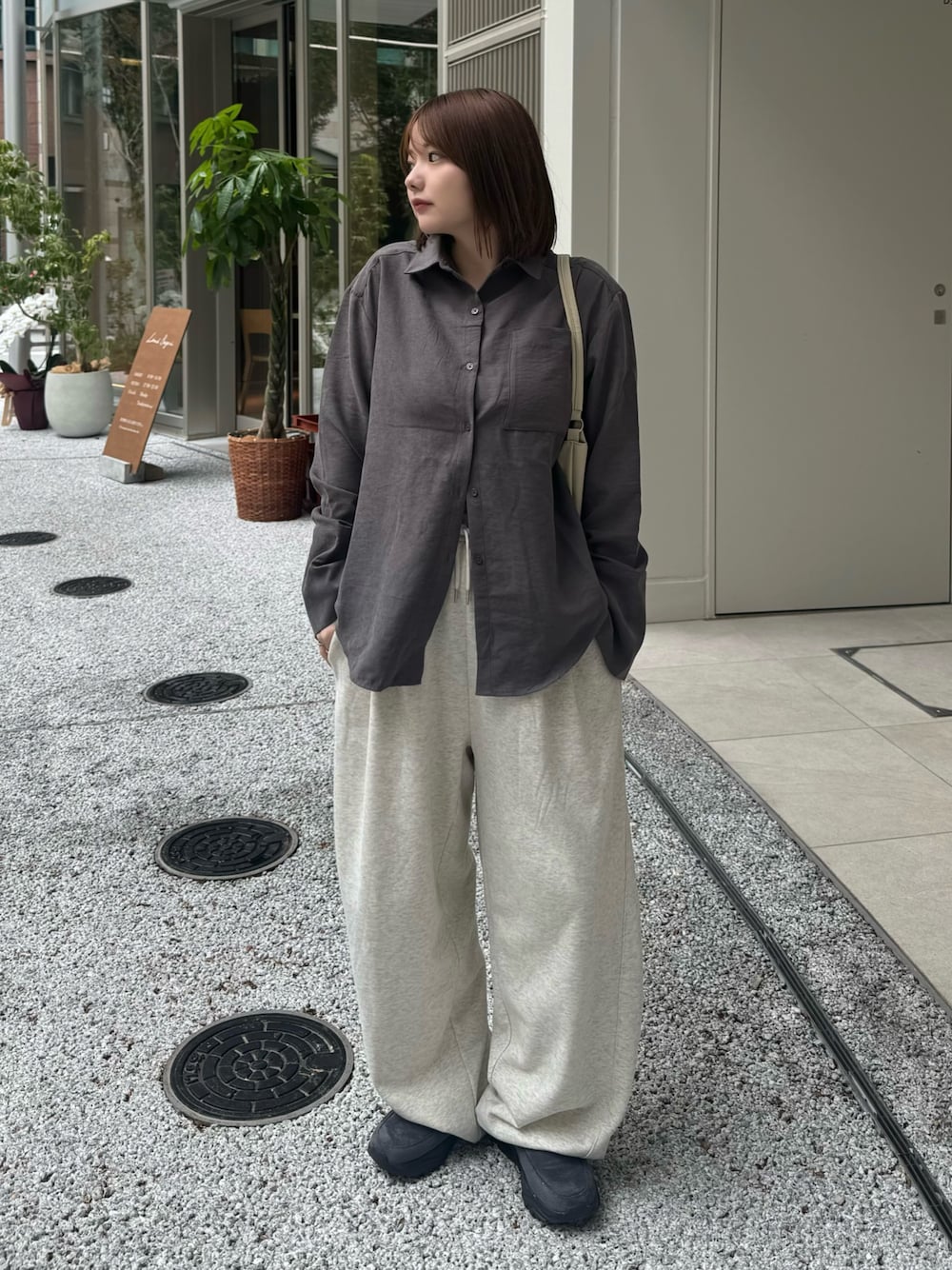 グレー系のシャツ/ブラウス、ベージュ系のスウェットパンツ、ホワイト系のハンドバッグを着用したレディースの秋コーディネートの1枚目の写真