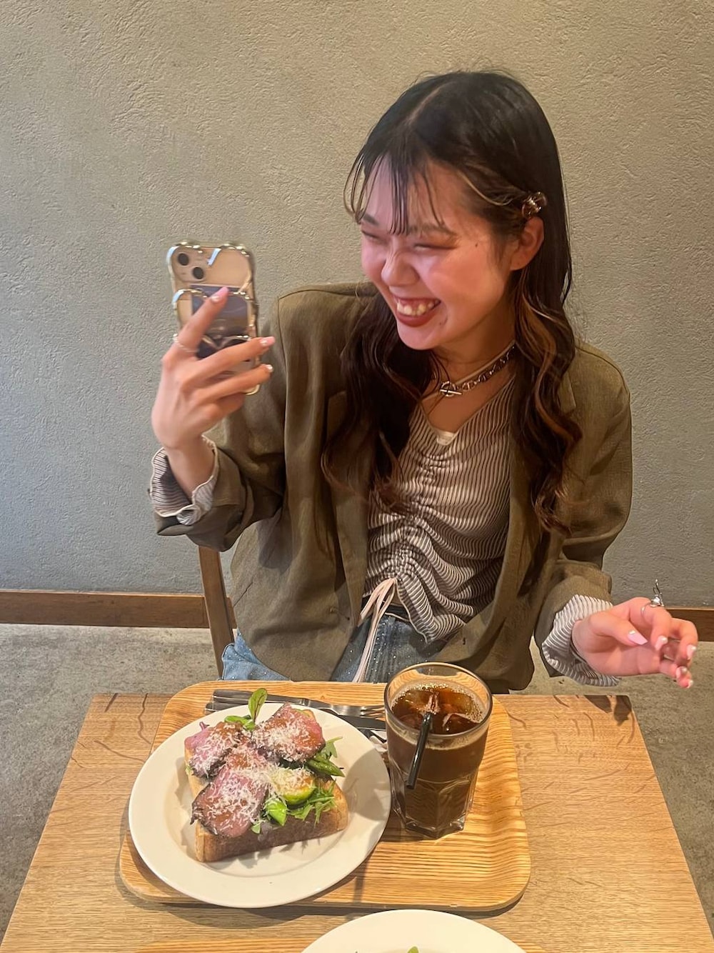 ブルー系のデニムパンツ、ブラック系のパンプス、ブラウン系のテーラードジャケットを着用したレディースの春コーディネートの1枚目の写真