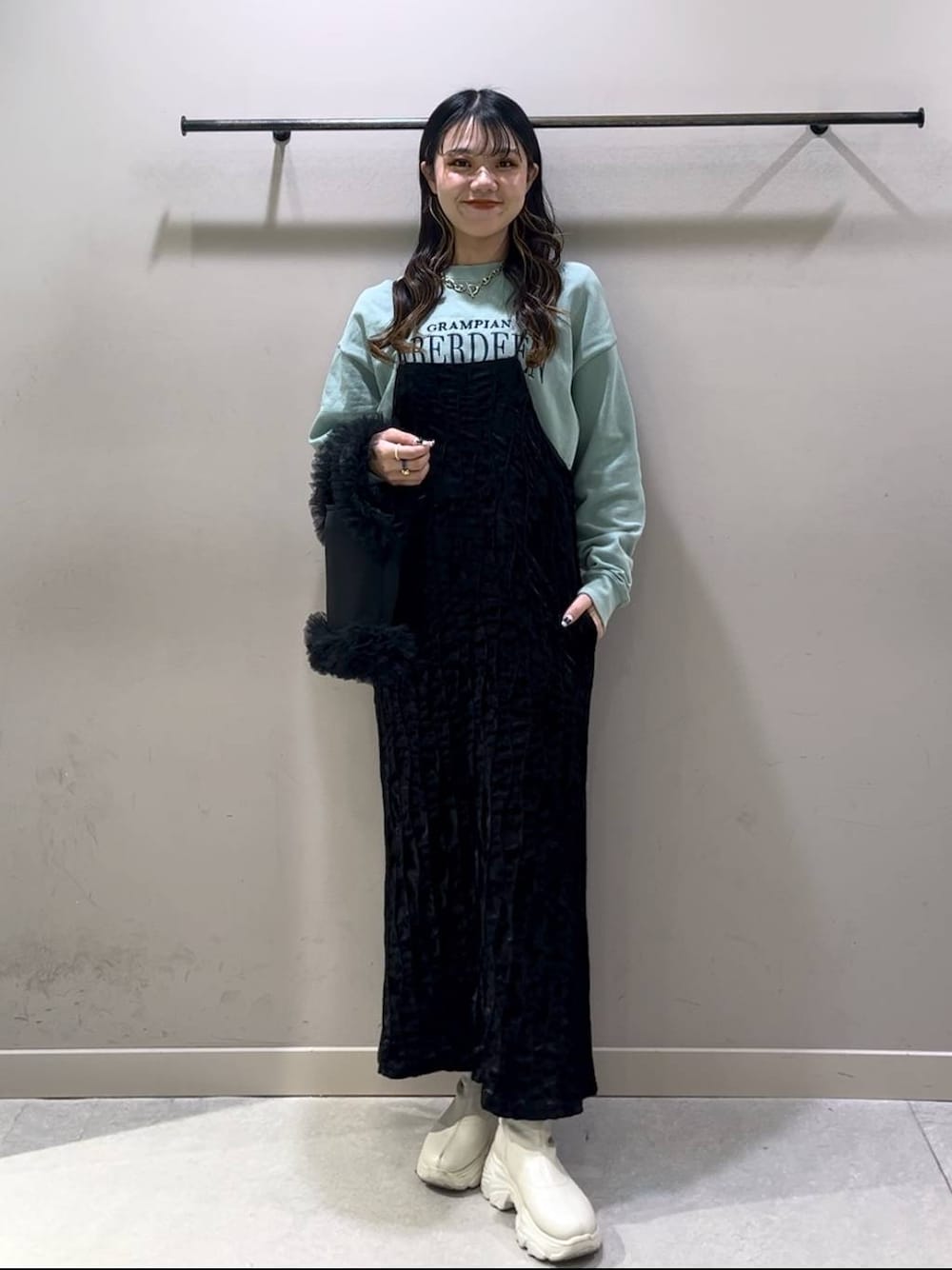 ホワイト系のブーツ、グリーン系のスウェット、ブラック系のワンピースを着用したレディースの冬コーディネートの1枚目の写真