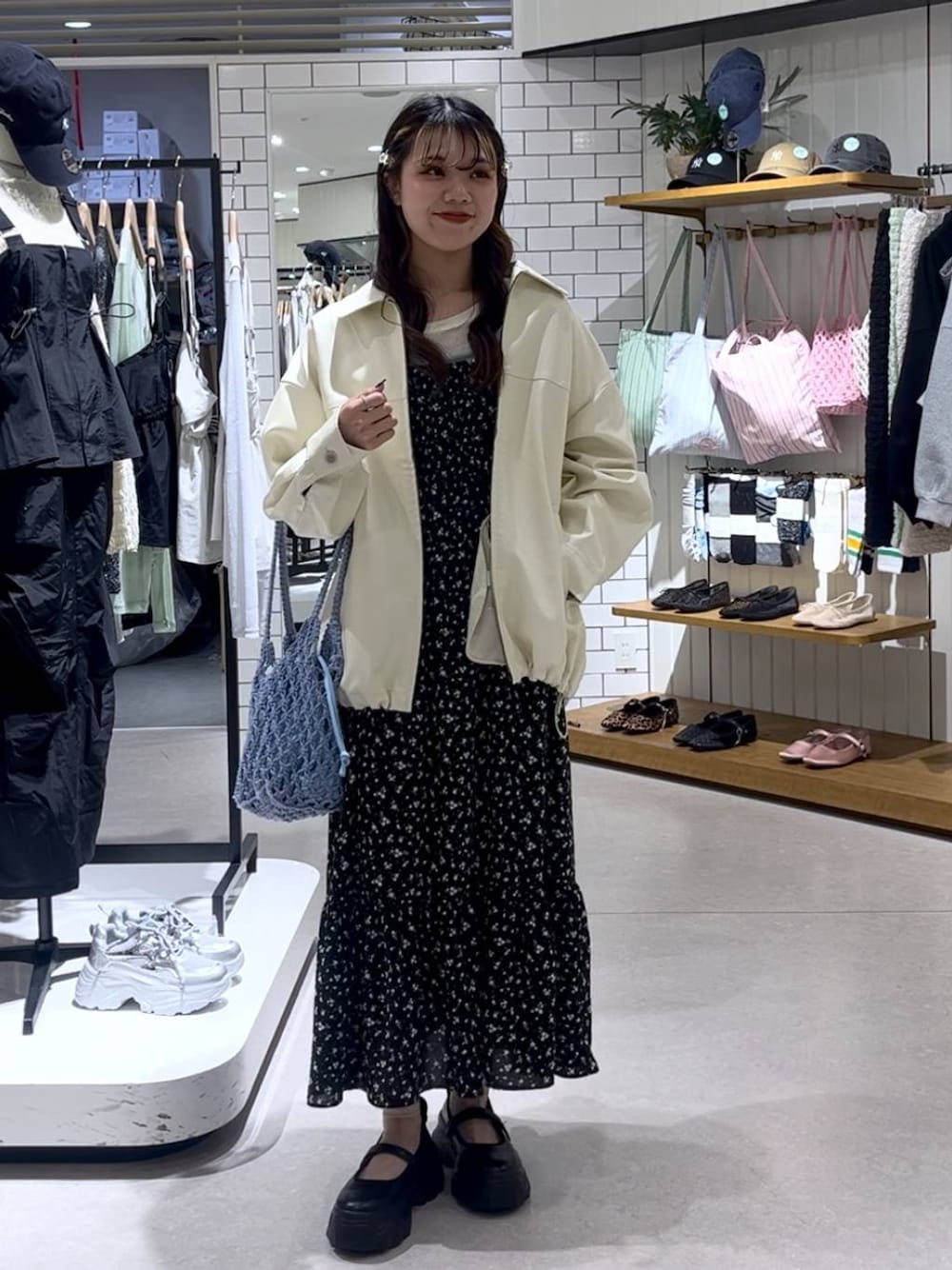 ブラック系のスニーカー、ブルー系のトートバッグ、ホワイト系のブルゾンを着用したレディースの春コーディネートの1枚目の写真