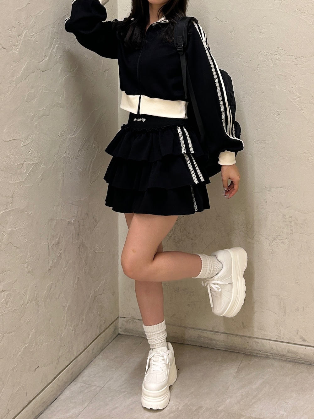 ブラック系のスウェット、ブラック系のスカート、ホワイト系のスニーカーを着用したレディースの秋コーディネートの1枚目の写真