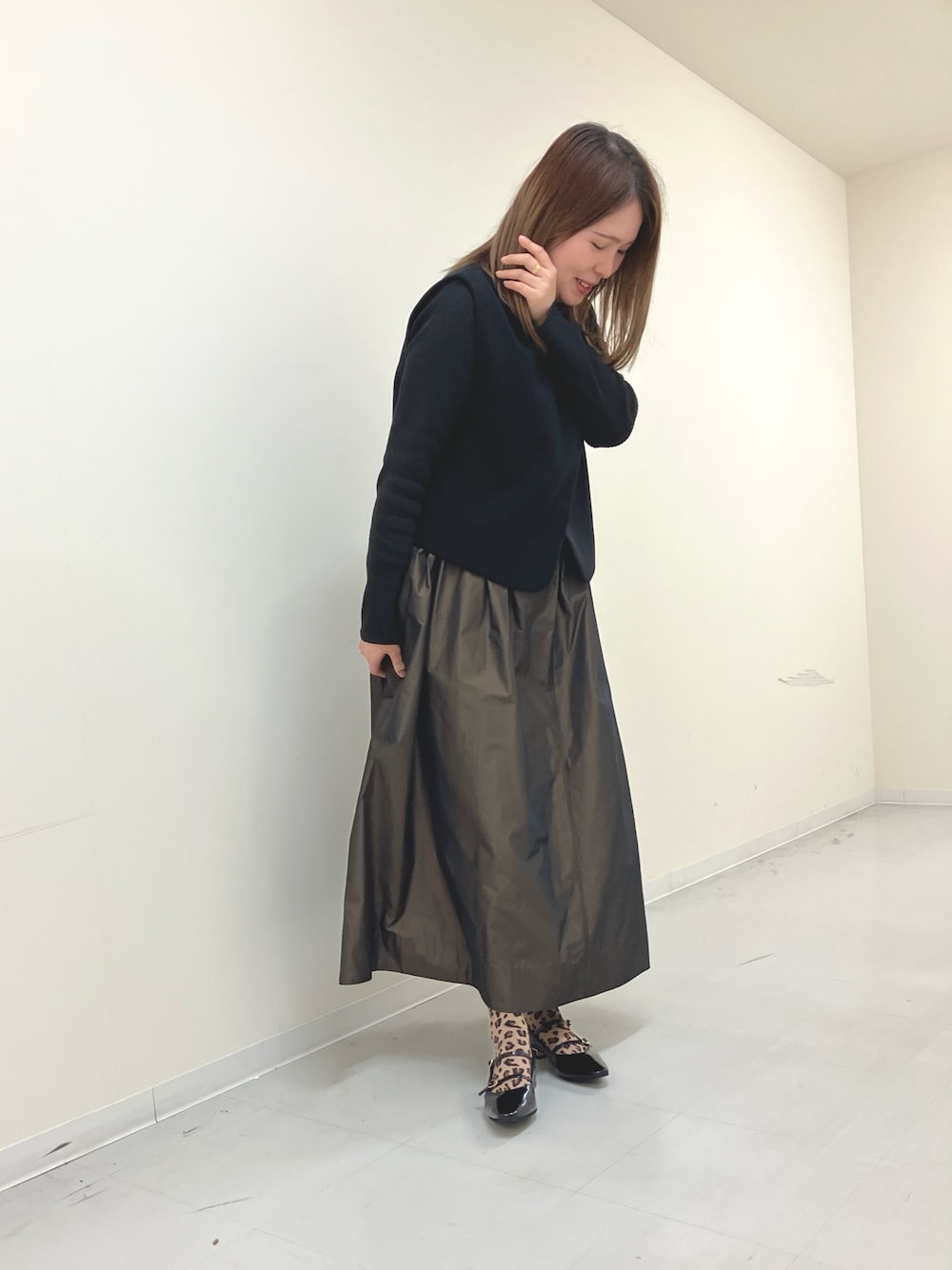 ブラック系のパンプスを着用したレディースの秋コーディネートの1枚目の写真