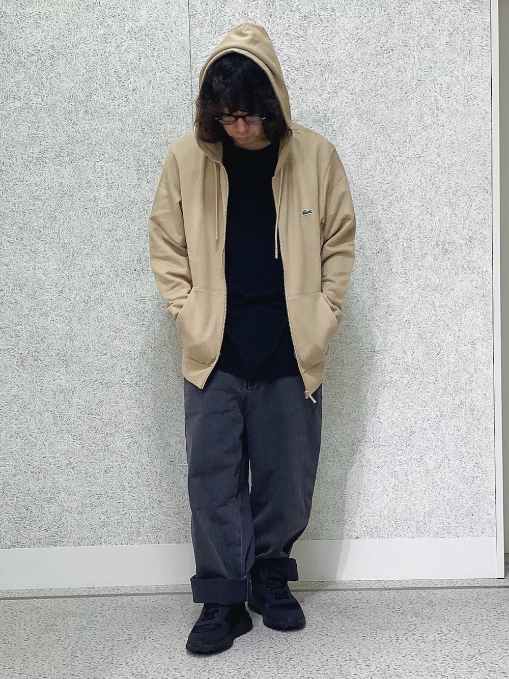 ブラック系のスニーカー、ブラック系のデニムパンツ、ベージュ系のパーカーを着用したメンズの秋コーディネートの1枚目の写真