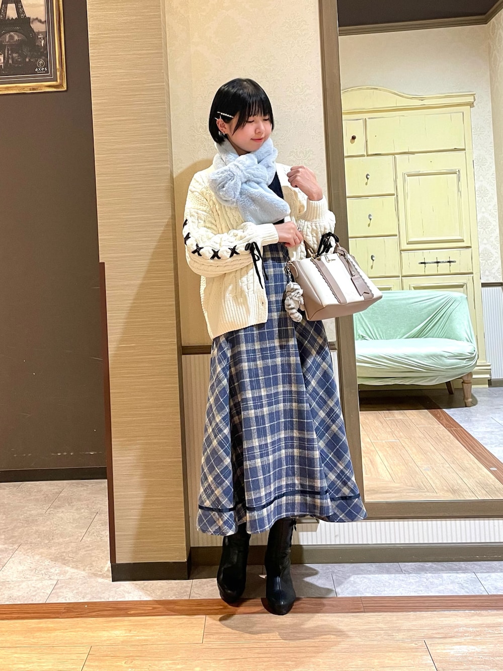 ブラック系のブーツ、ホワイト系のカーディガン/ボレロ、ブルー系のスカートを着用したレディースの秋コーディネートの1枚目の写真