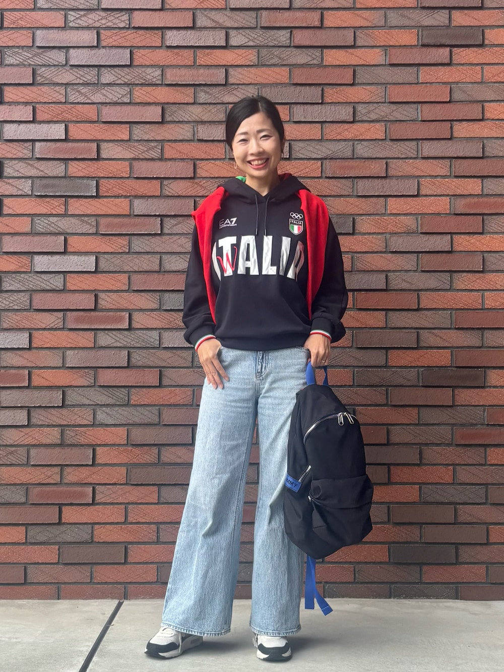 ブラック系のパーカー、ブルー系のデニムパンツ、ブラック系のバックパック/リュックを着用したレディースの秋コーディネートの1枚目の写真