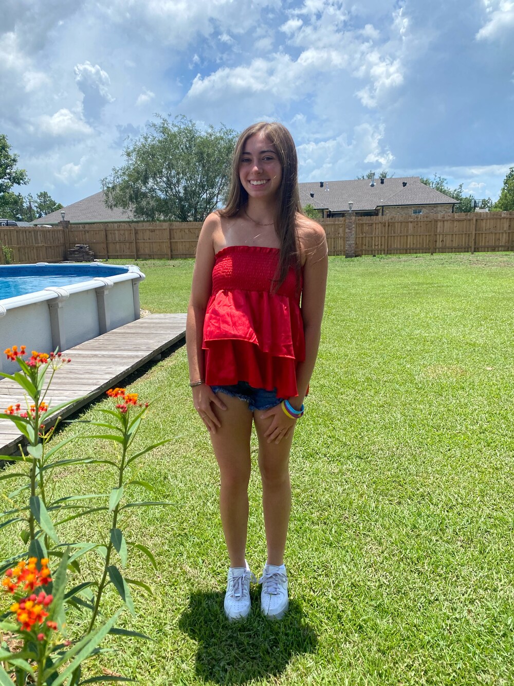 ホワイト系のスニーカー、レッド系のスカート、ブルー系のデニムパンツを着用したレディースの夏コーディネートの1枚目の写真