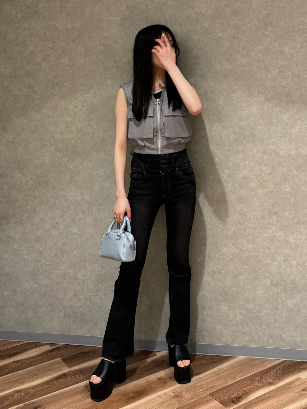 ブラック系のハンドバッグ、ブラック系のデニムパンツ、ブラック系のサンダルを着用したレディースの春コーディネートの1枚目の写真