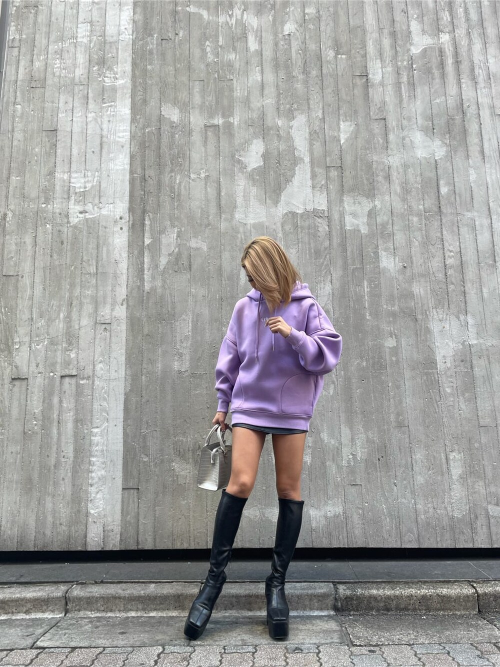 パープル系のTシャツ/カットソー、ブラック系のブーツ、ブラック系のスカートを着用したレディースの冬コーディネートの1枚目の写真