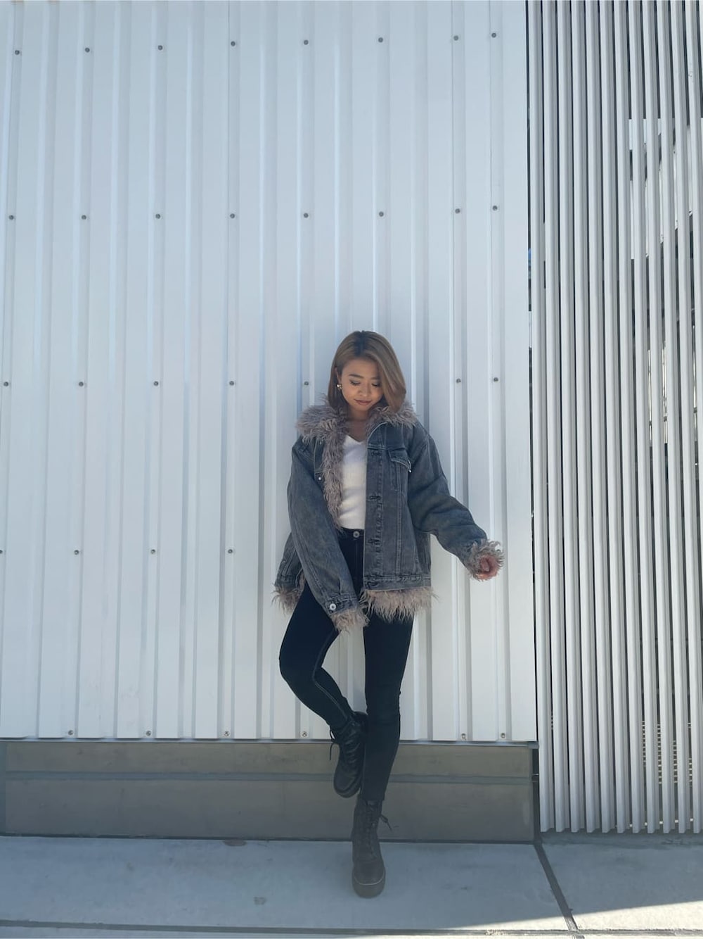 ブラック系のブーツ、ブラック系のデニムパンツ、ホワイト系のニット/セーターを着用したレディースの秋コーディネートの1枚目の写真