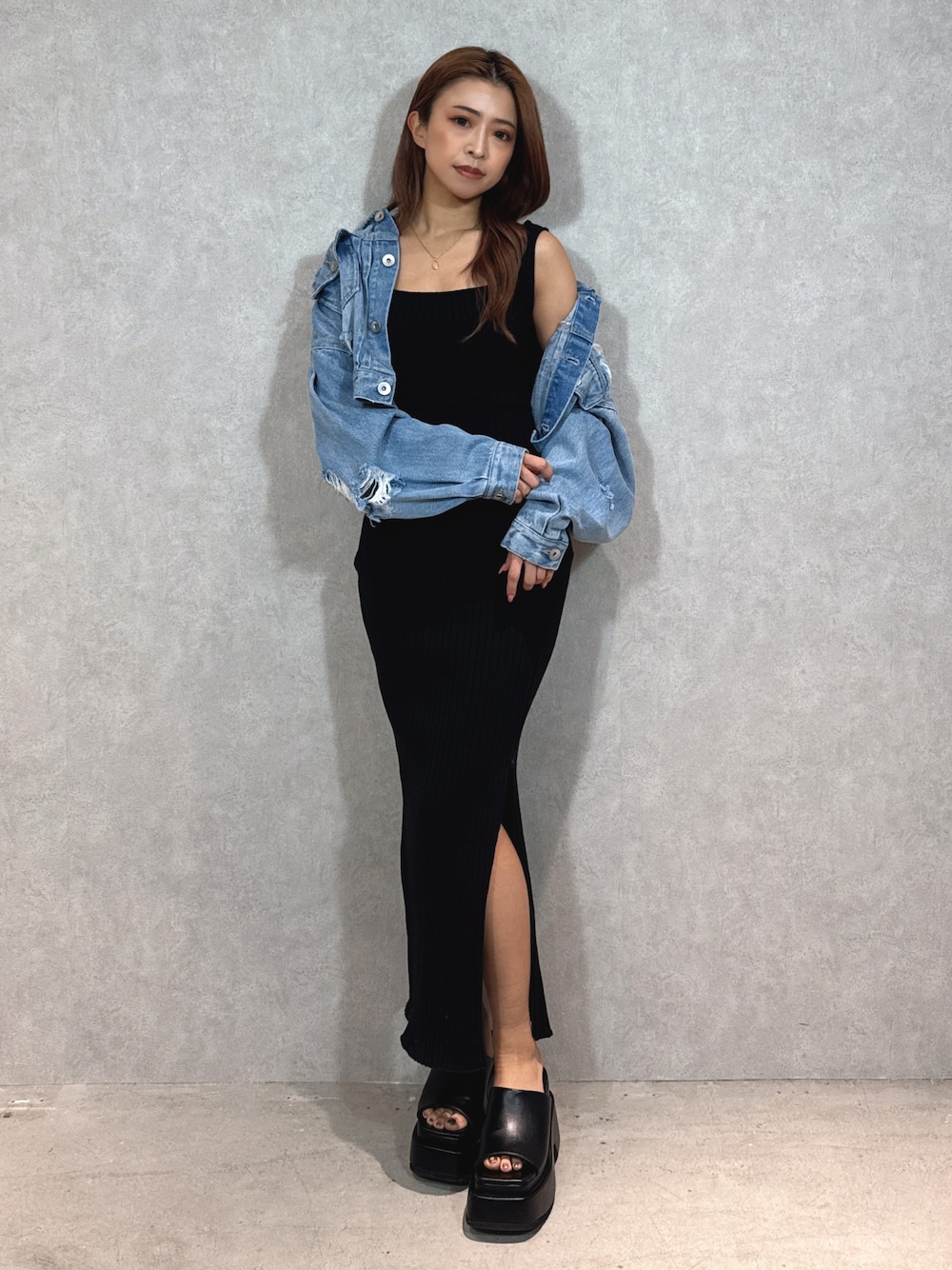 ブラック系のワンピース、ブルー系のデニムジャケット、ブラック系のサンダルを着用したレディースの春コーディネートの1枚目の写真