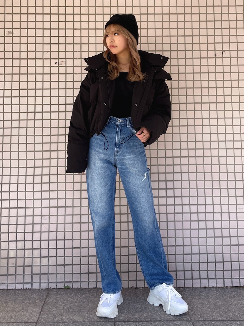 ホワイト系のスニーカー、ブルー系のデニムパンツ、ブラック系のニット/セーターを着用したレディースの冬コーディネートの1枚目の写真