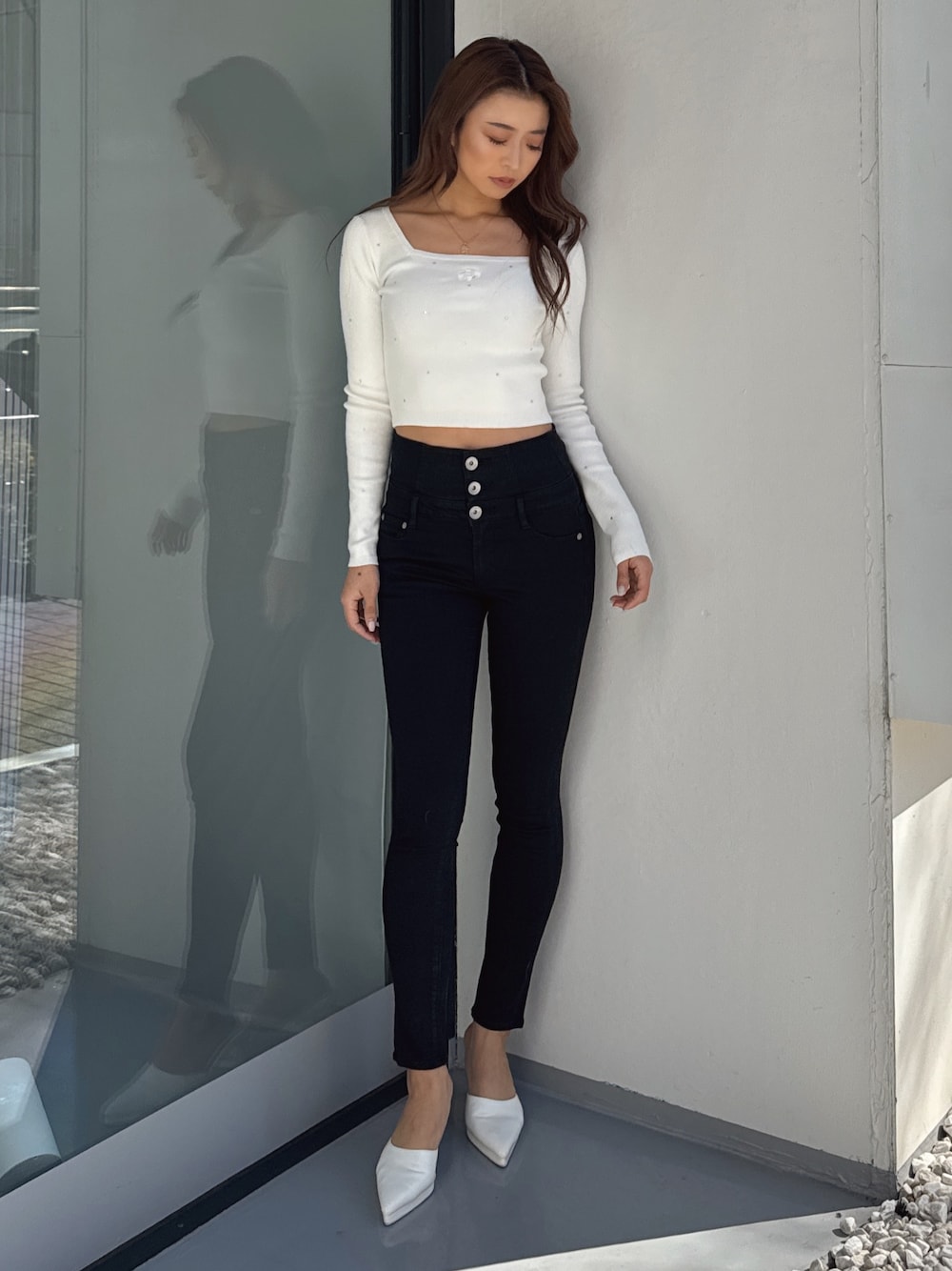 ホワイト系のニット/セーター、ブラック系のデニムパンツ、ホワイト系のパンプスを着用したレディースの春コーディネートの1枚目の写真