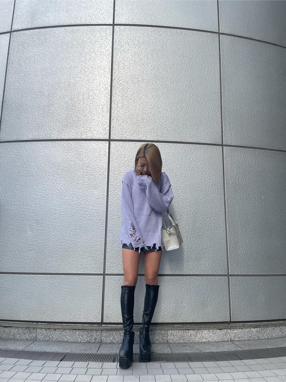 パープル系のニット/セーター、グレー系のハンドバッグ、ブラック系のブーツを着用したレディースの冬コーディネートの1枚目の写真