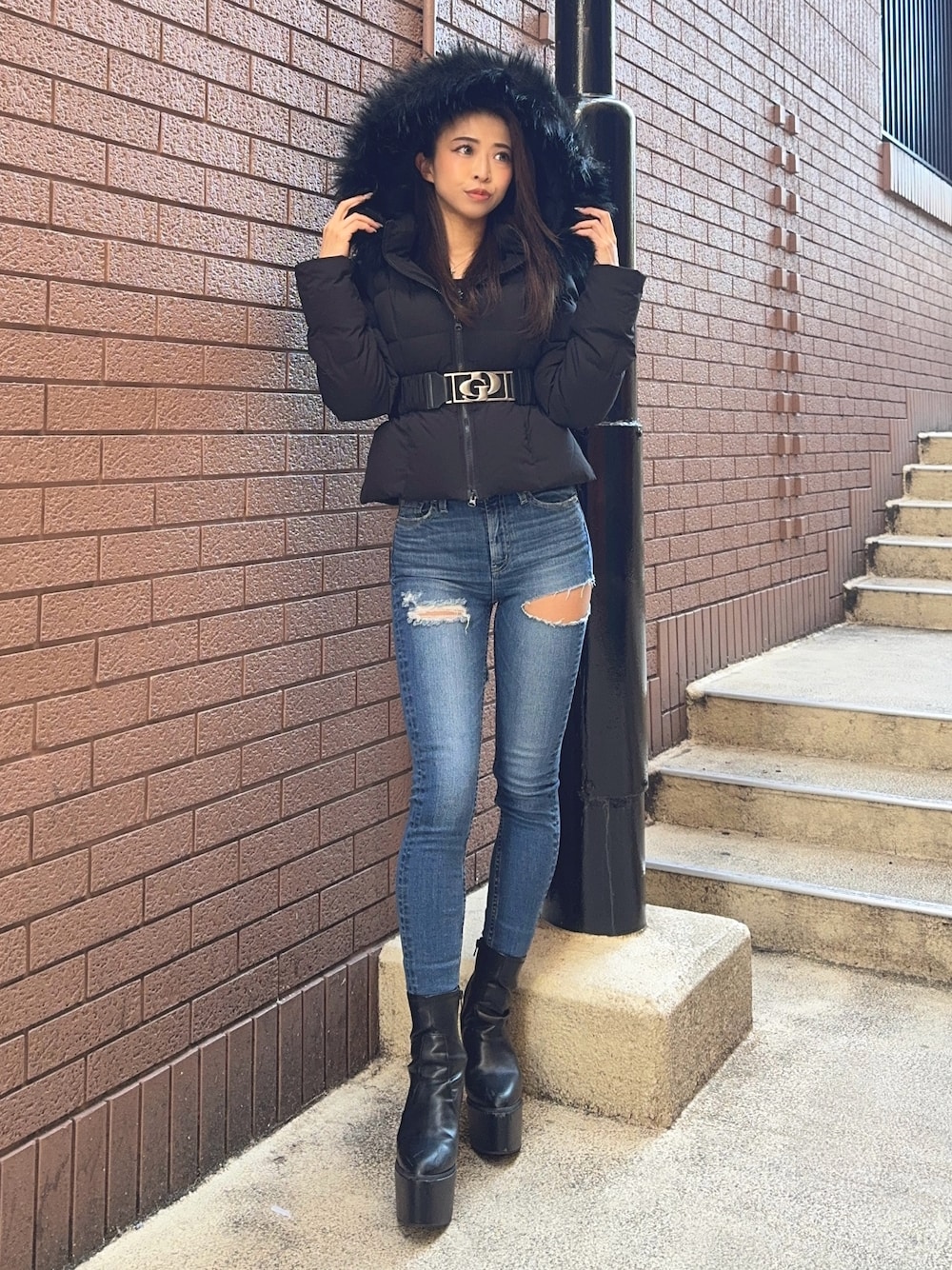 ブラック系のダウンジャケット/コート、ブラック系のニット/セーター、ブルー系のデニムパンツを着用したレディースの秋コーディネートの1枚目の写真