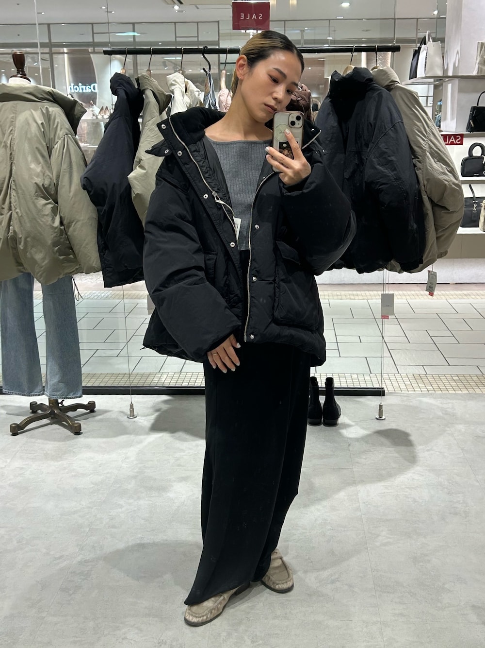 ブラック系のスカート、ブラック系のダウンジャケット/コート、グレー系のニット/セーターを着用したレディースの冬コーディネートの1枚目の写真