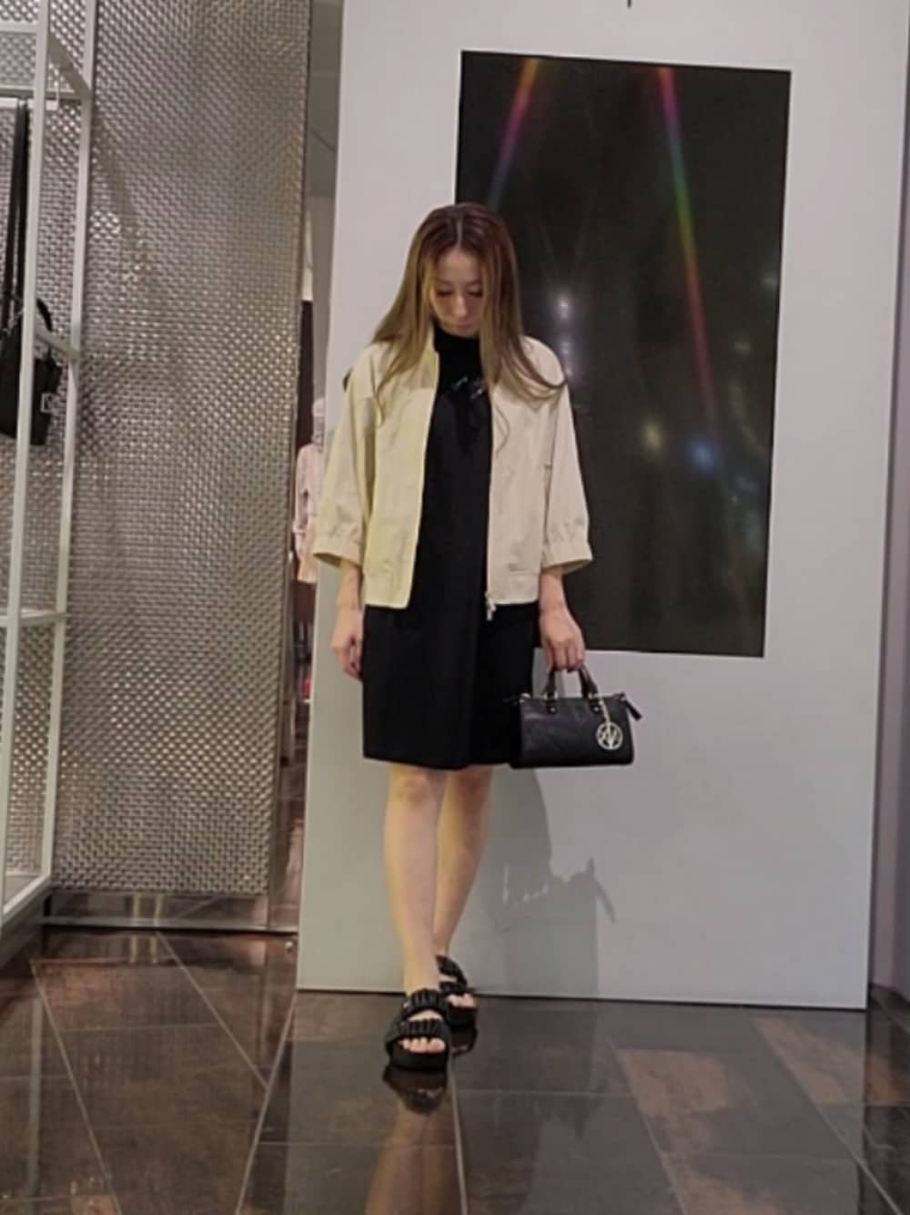 ブラック系のハンドバッグ、ブラック系のサンダル、ブラック系のワンピースを着用したレディースの秋コーディネートの1枚目の写真