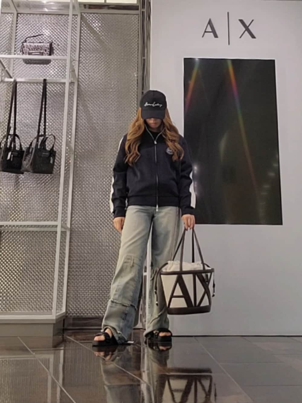 ブルー系のデニムパンツ、ブラック系のサンダル、ブラウン系のトートバッグを着用したレディースの夏コーディネートの1枚目の写真