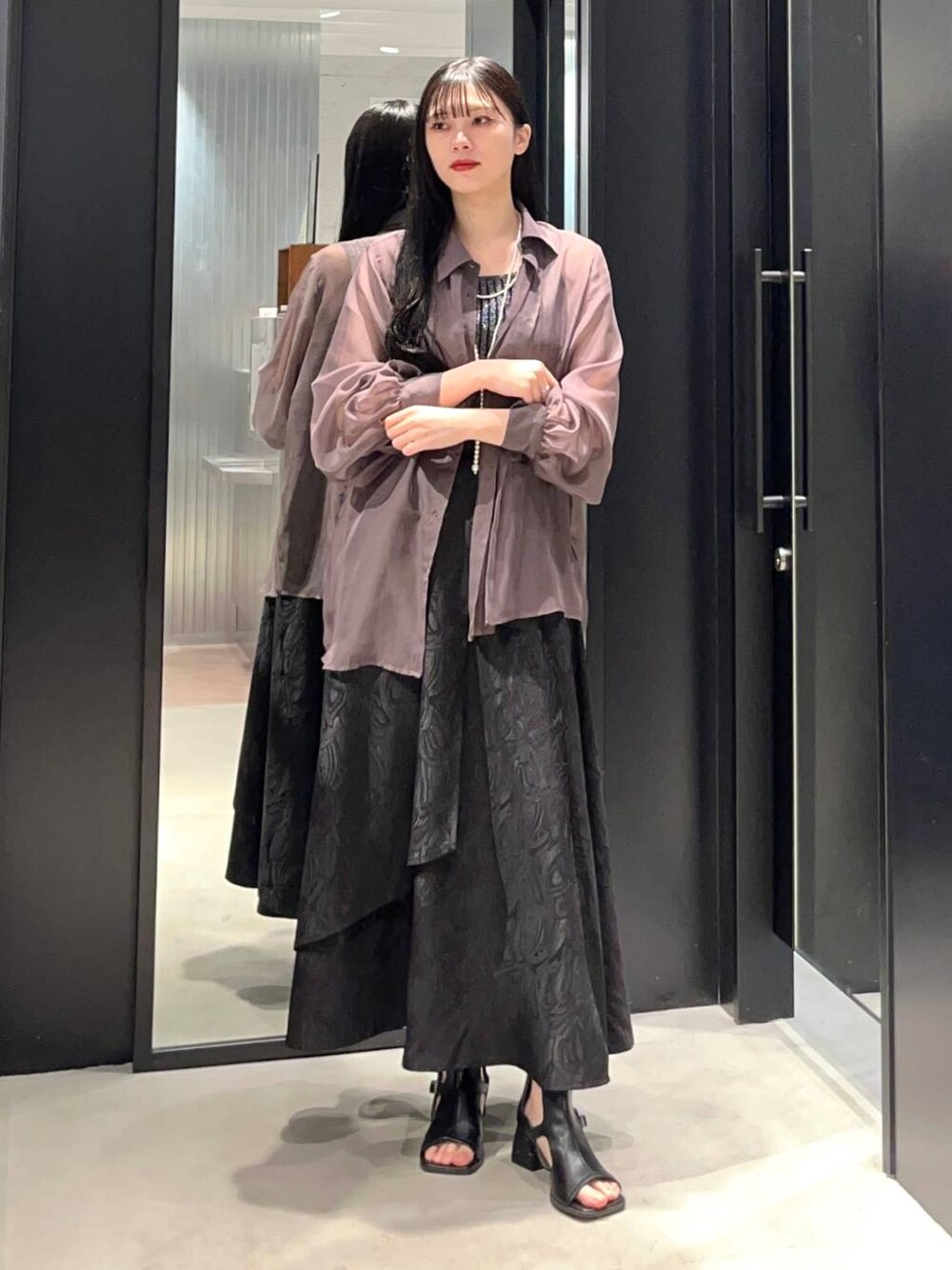 ベージュ系のシャツ/ブラウス、ブラック系のスカート、ブラック系のタンクトップを着用したレディースの春コーディネートの1枚目の写真