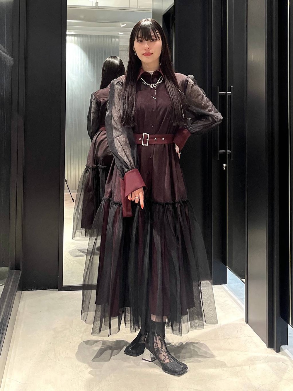 ブラック系のブーツ、レッド系のワンピース、シルバー系のネックレスを着用したレディースの春コーディネートの1枚目の写真