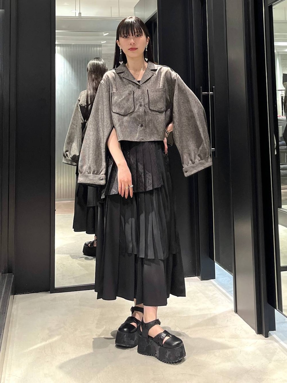 ブラック系のサンダル、ブラック系のスカート、ブラック系のシャツ/ブラウスを着用したレディースの春コーディネートの1枚目の写真